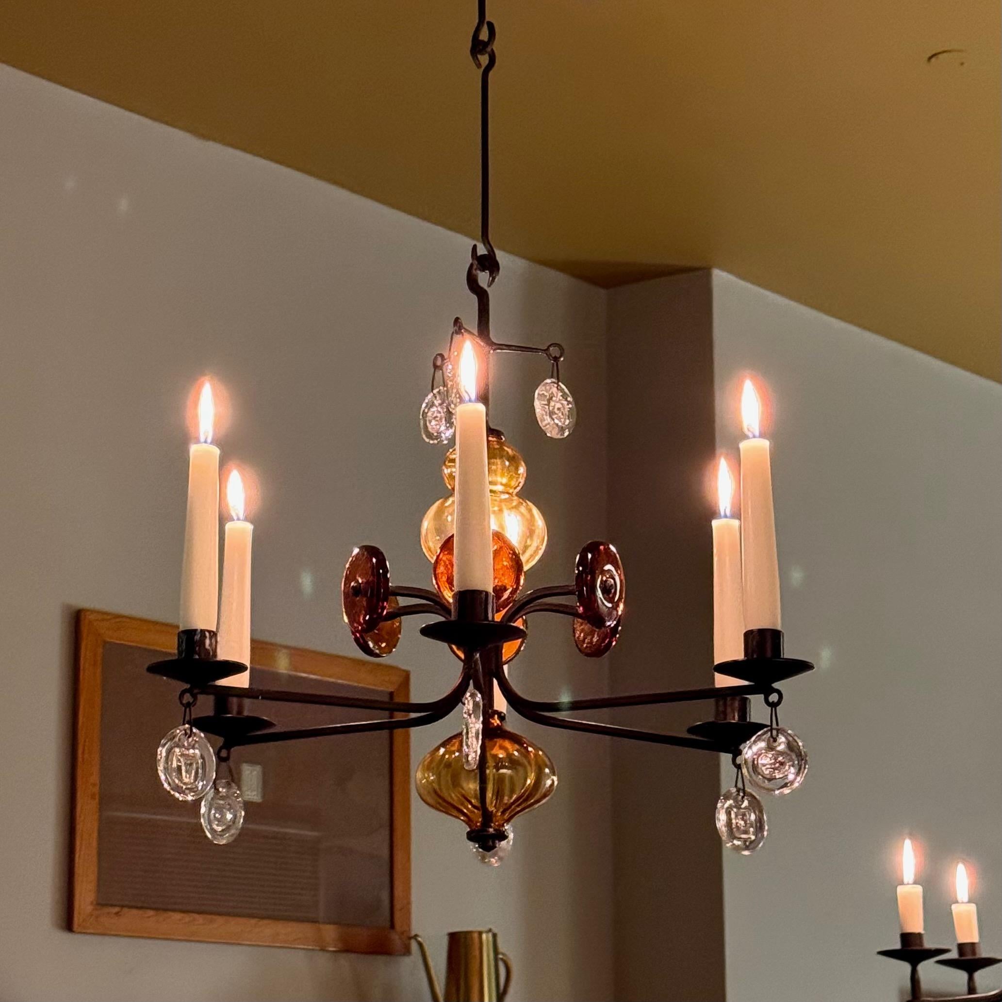 Descrizione:
Lampadario in ferro battuto e vetro pressato progettato da Erik Höglund per Kosta Boda negli anni Sessanta. La struttura in ferro battuto annerito di questo lampadario a 6 bracci è ornata da una spumeggiante costellazione di tondi in