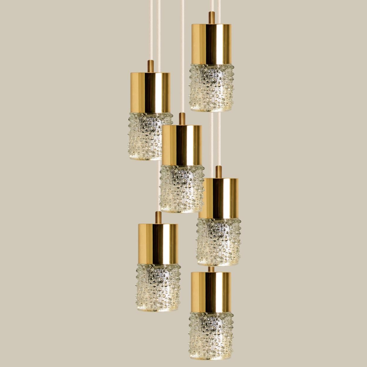 6 brass and glass pendant lights, made in 1970s in Germany, Europe.
The lights consists of a brassed plastic tube with tubular glass lampshade made of clear pressed glass.
The light can be hung separate or as a cascade, as shown in the