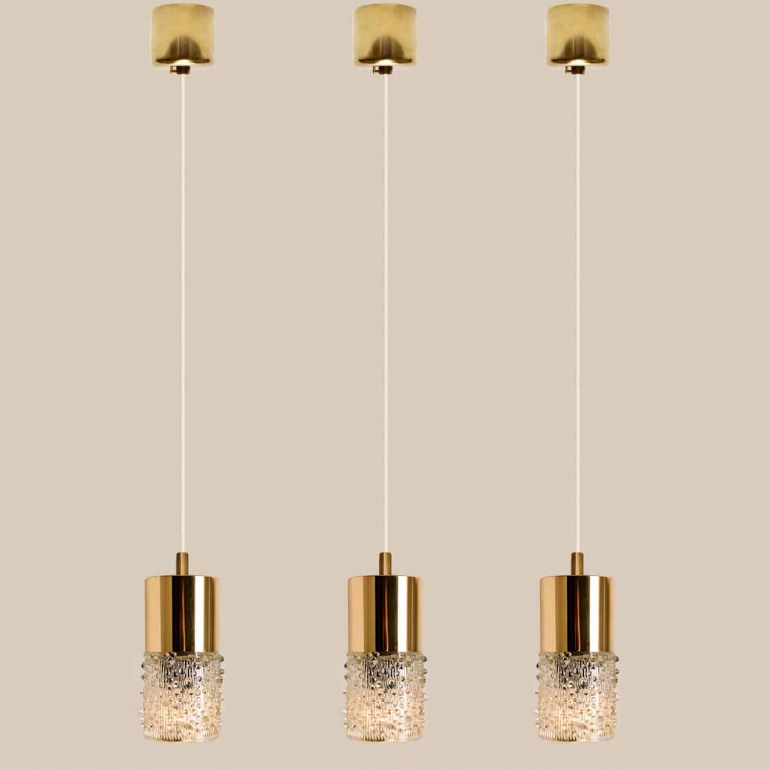 6 brass and glass pendant lights, made in 1970s in Germany, Europe.
The lights consists of a brassed plastic tube with tubular glass lampshade made of clear pressed glass.
The light can be hung separate or as a cascade, as shown in the images.

The