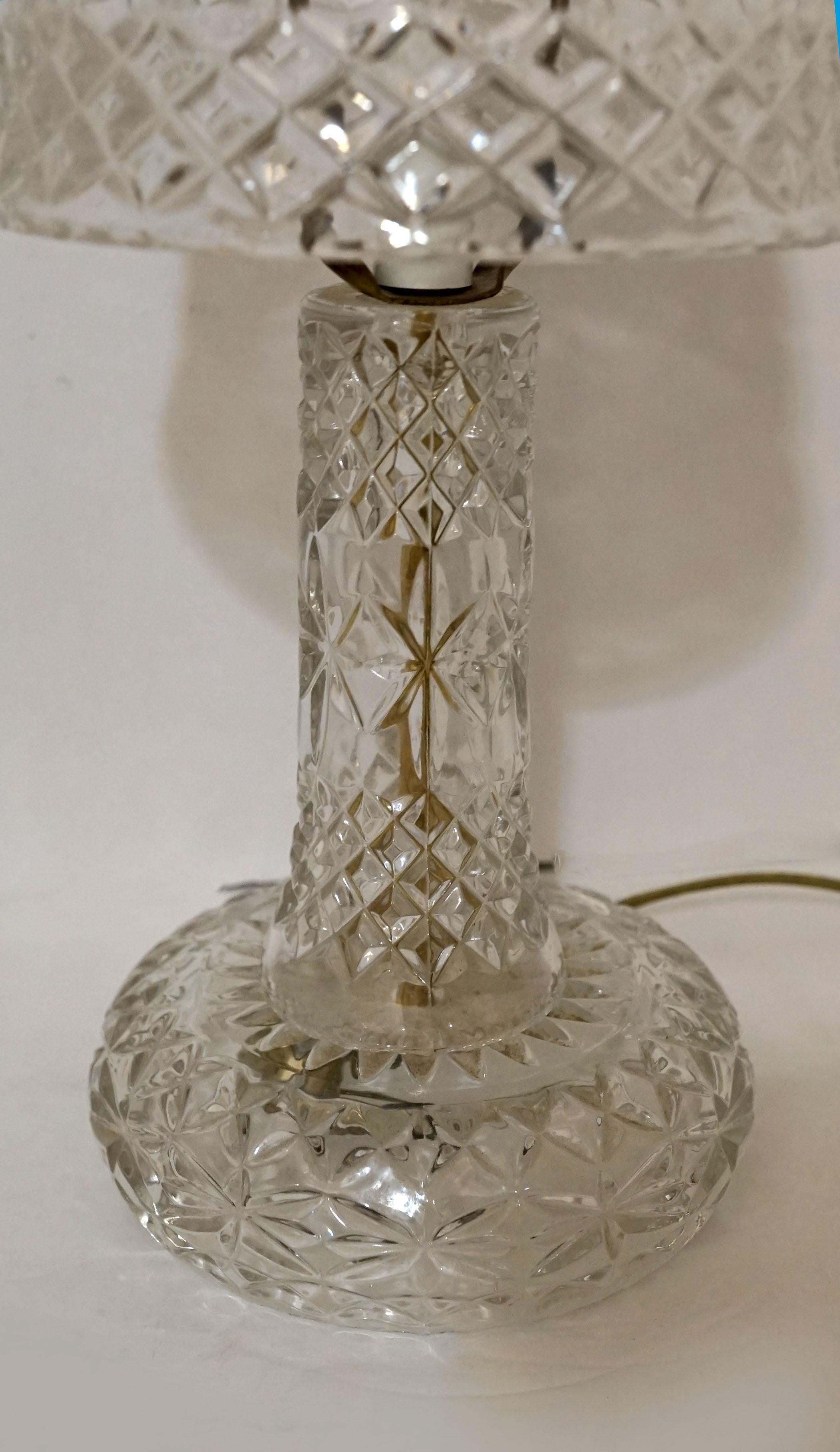 This is a rare crystal lamp that is topped with a shade that is formed like a mushroom cap. The lamp is pressed leaded crystal and is either American or English from the mid 20th century. 
There is a diamond and star pattern throughout, and the