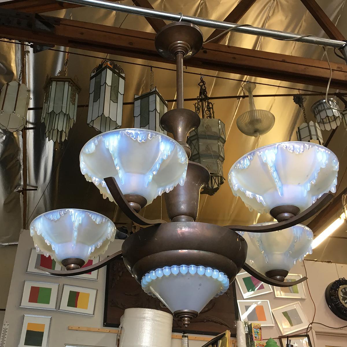 This Art Deco chandelier with five-arm design and center light with pressed molded Vaseline glass shades with an icicle theme. The Chandelier is constructed from bronze and finished in antique patina. Each arm is centered despite the curvaceousness