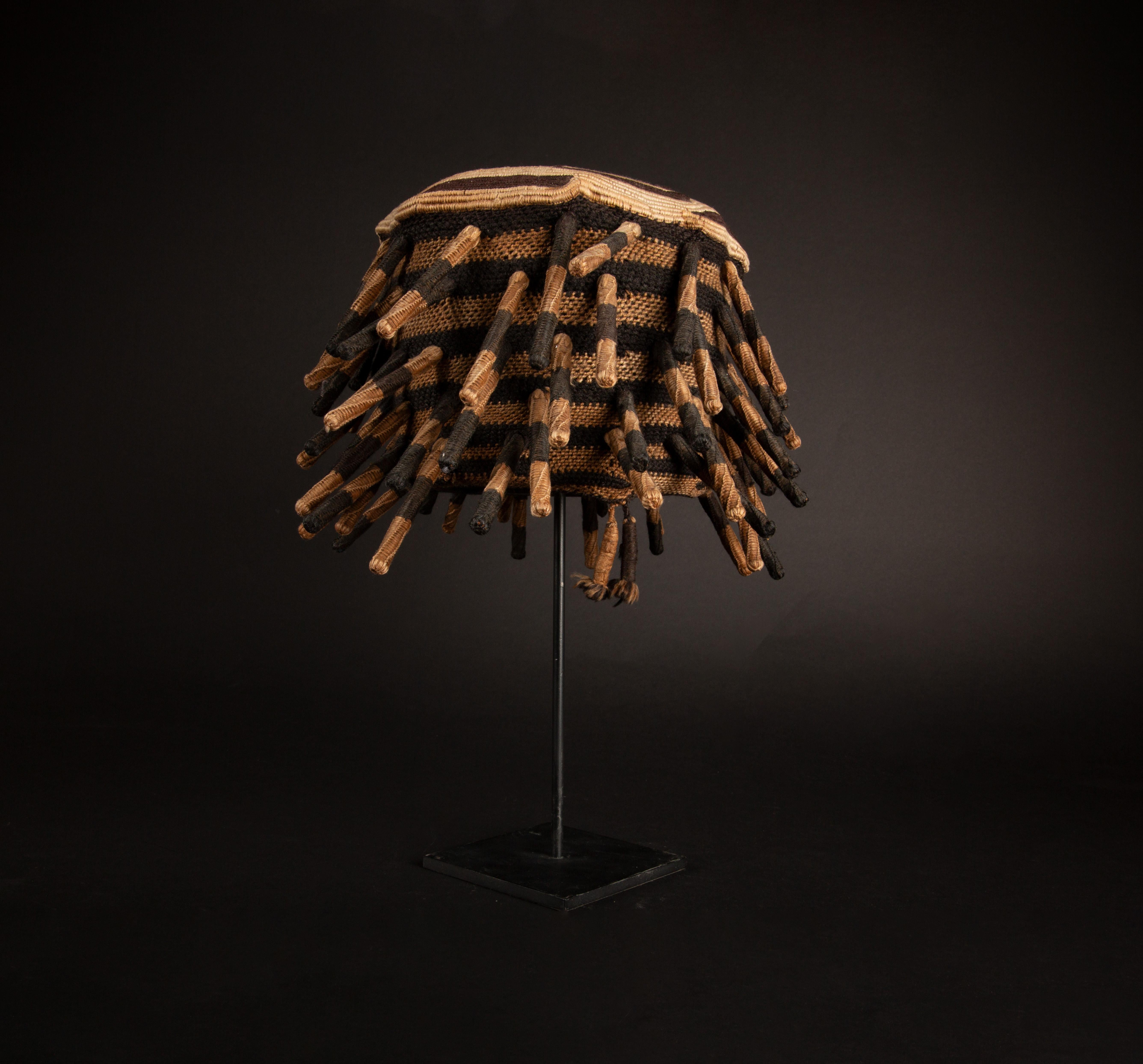 Adorned with spiked braids, this prestigious custom mounted Ashetu hat embodies the cultural significance of the Bamum and Bamileke people of Cameroon, Central Africa, who revered the human head as the vessel of one's spirit and intellect. In their