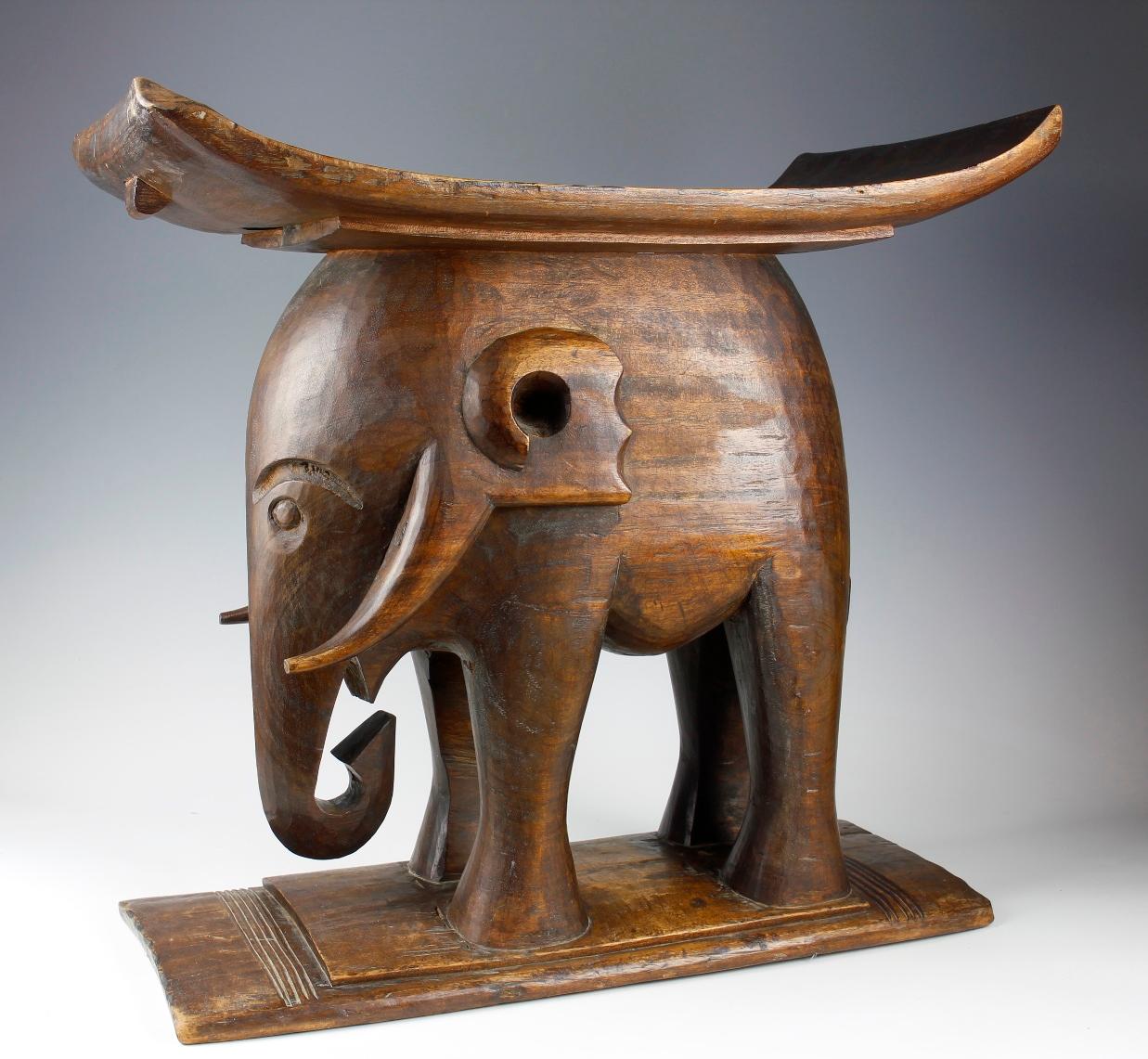Dieser schöne frühe Hocker aus der Ashanti-Kultur in Ghana stellt einen Elefanten dar - ein Symbol der Ashanti für Macht und Stärke. Dieser große, beeindruckende Hocker, der aus schwerem, braunem Holz geschnitzt ist, hatte neben seinem funktionalen