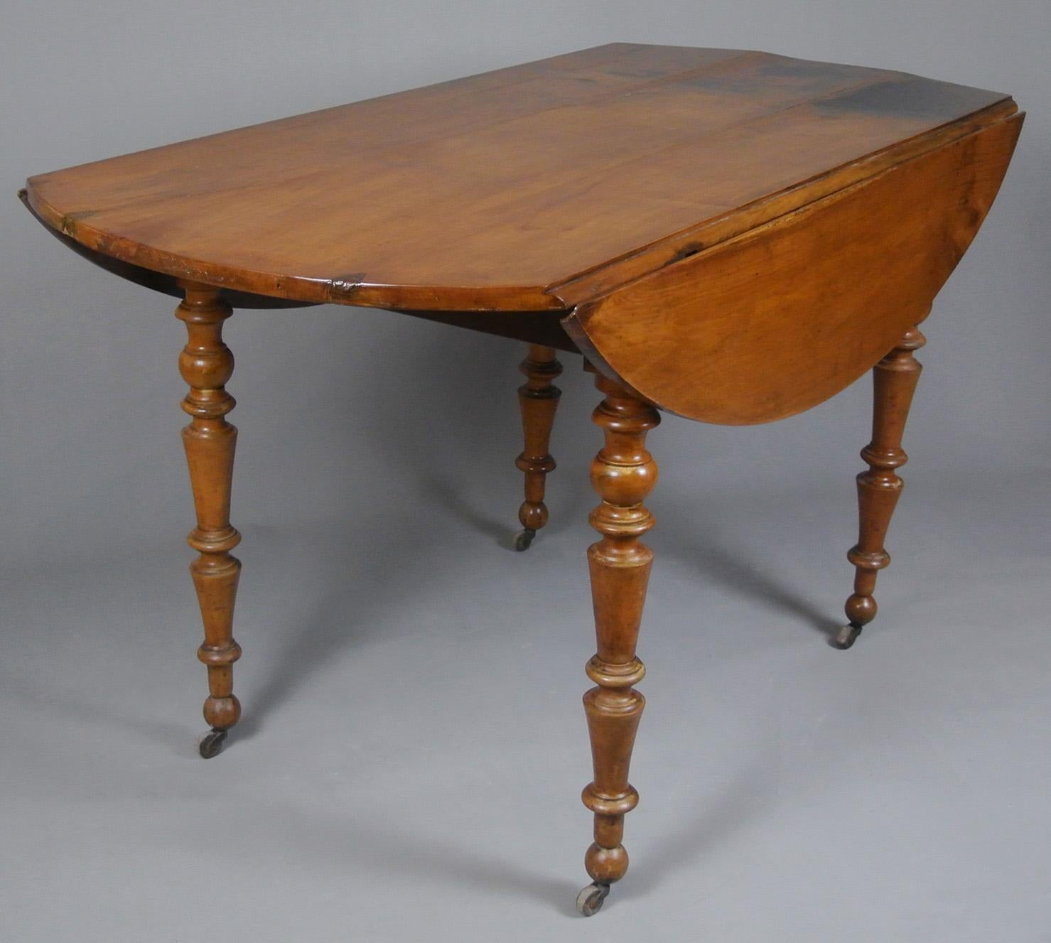 A very pretty 19th Century table, French, and made from a beautifully coloured fruitwood and dating from around 1880. The three plank top with two drop leaves which rise and are supported on pull out lopers with original iron ring handles.

The