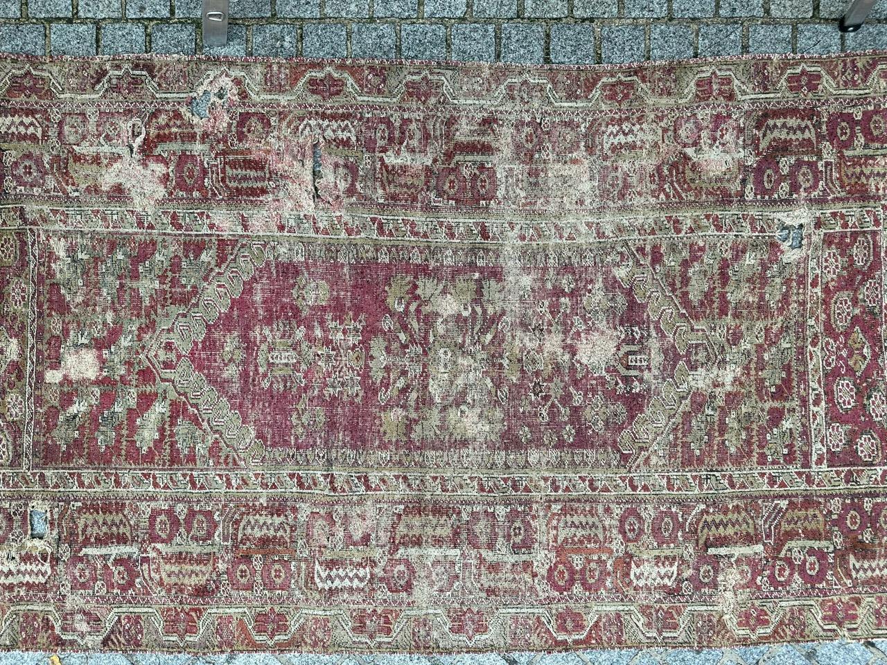 Exquisite 200-year-old Ottoman rug from the Ghyordes region in Turkey. This remarkable piece features intricate geometric and stylized patterns, with lovely natural hues of purple and orange as the background. The border is adorned with geometric