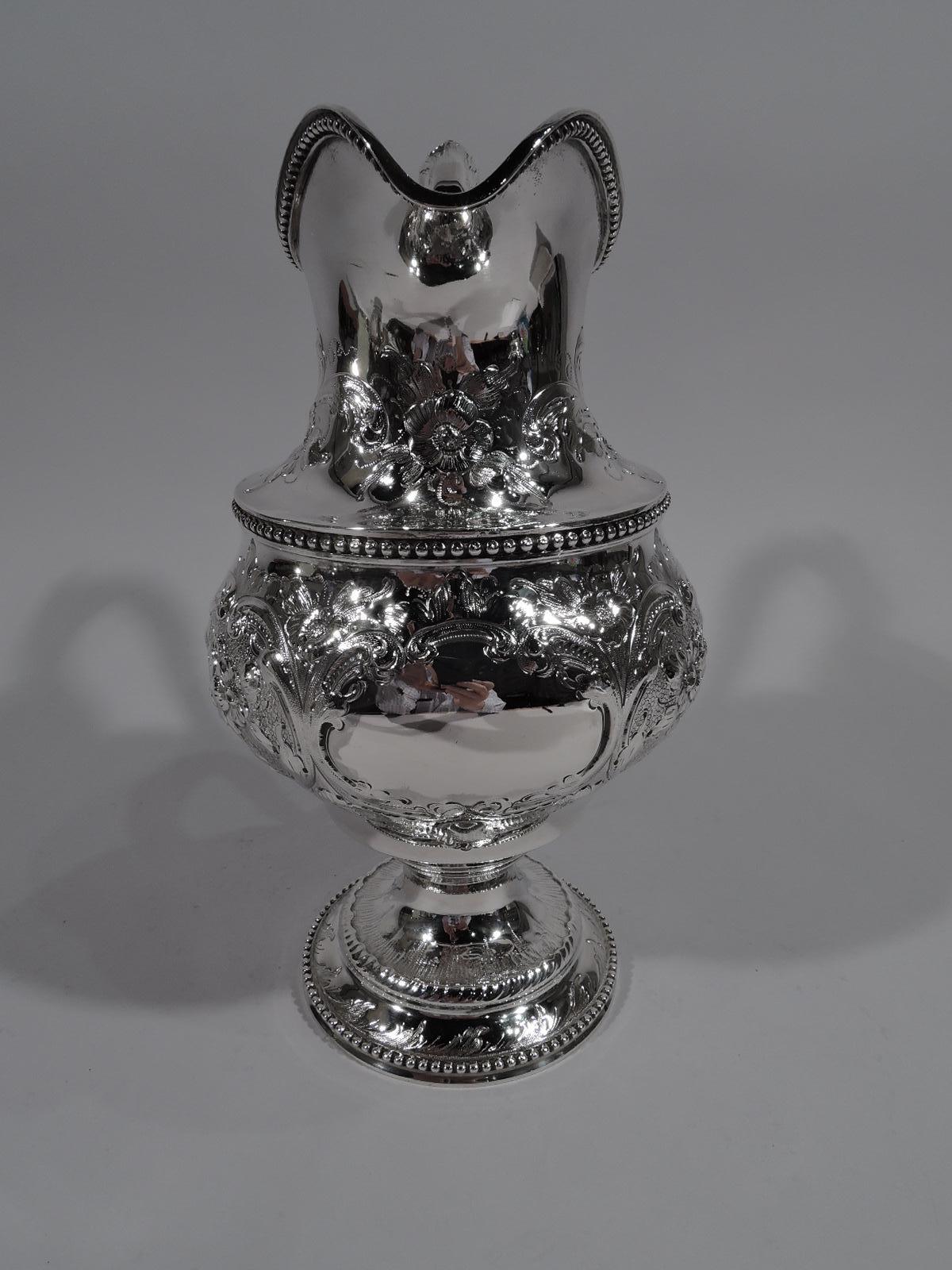 Fresh and pretty American coin silver pitcher. Baluster body with helmet mouth, leaf-capped s-scroll handle, and stepped support. Engraved and repousse flowers and leaves, and scrolled cartouche (vacant). Beading. Indistinct mark appears to be for