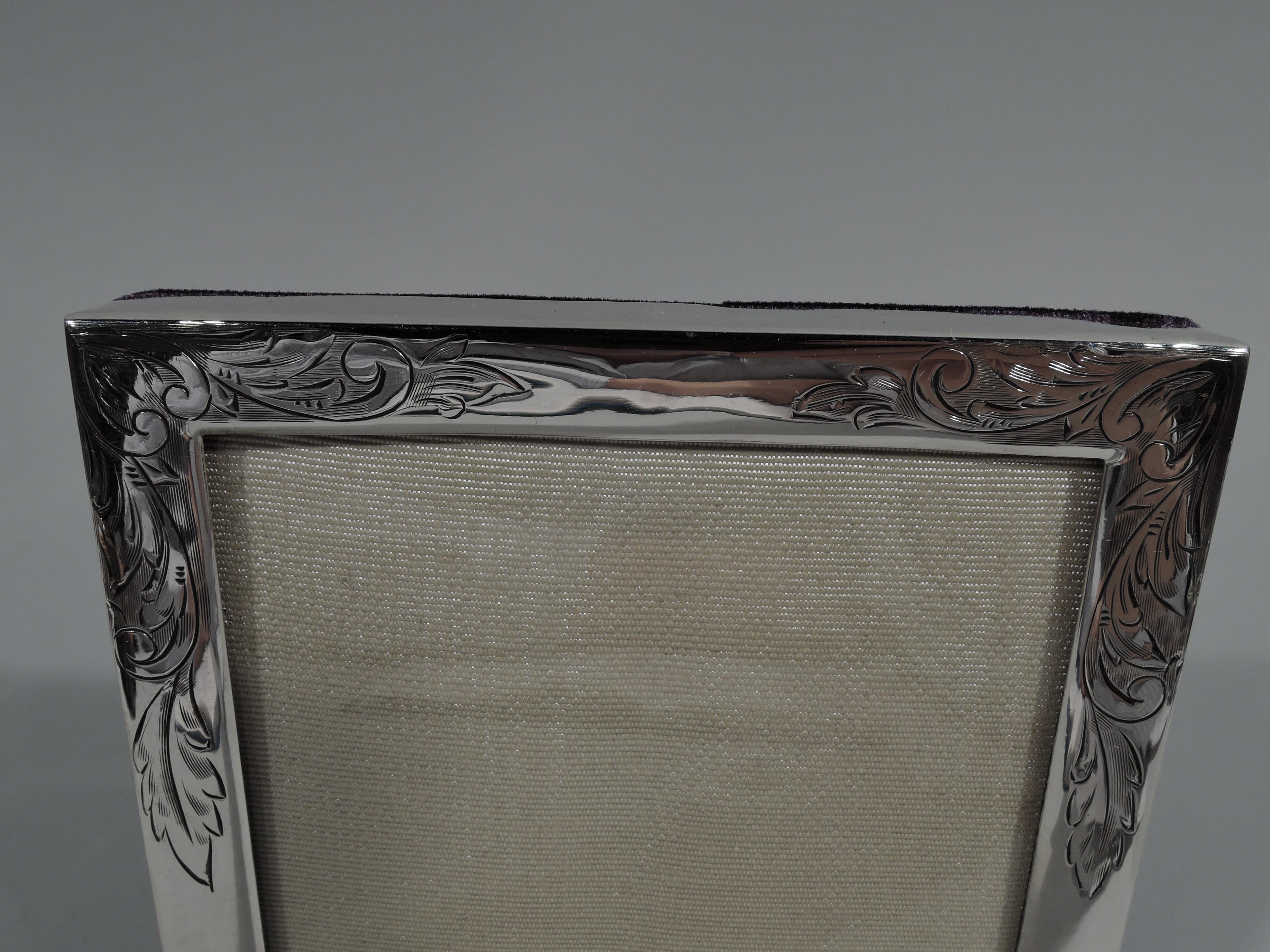 Pretty American sterling silver picture frame. Rectangular window and surround engraved with loose and flowing leaf scrolls. With glass, silk lining, and velvet back and hinged support for portrait (vertical) display. Fully marked including no. 23