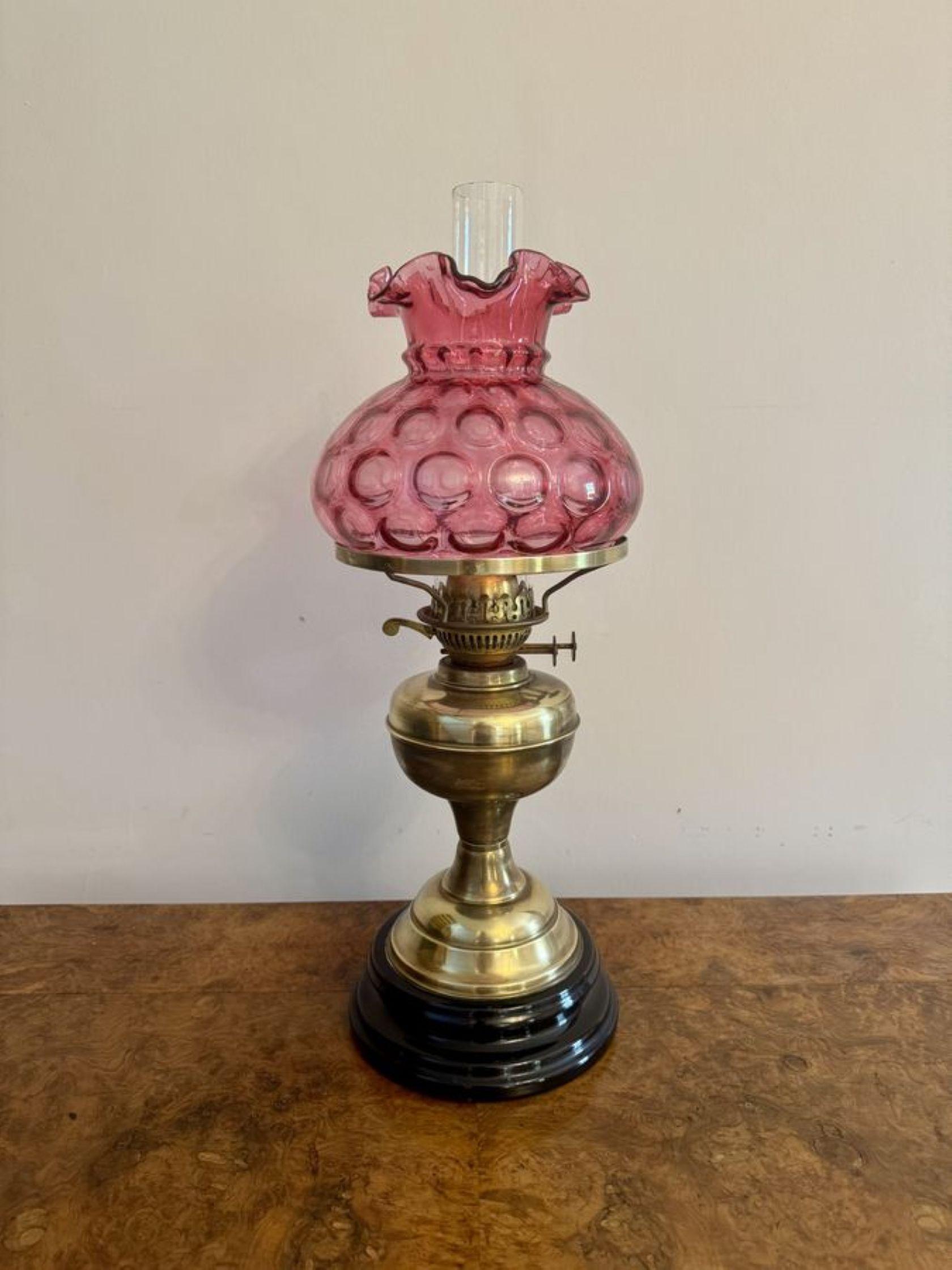 Jolie lampe à huile en laiton de l'époque édouardienne avec un abat-jour en verre à la canneberge, avec un bel abat-jour en verre à la canneberge avec un sommet ondulé, un double brûleur en laiton au-dessus d'une façade en laiton soutenue par une