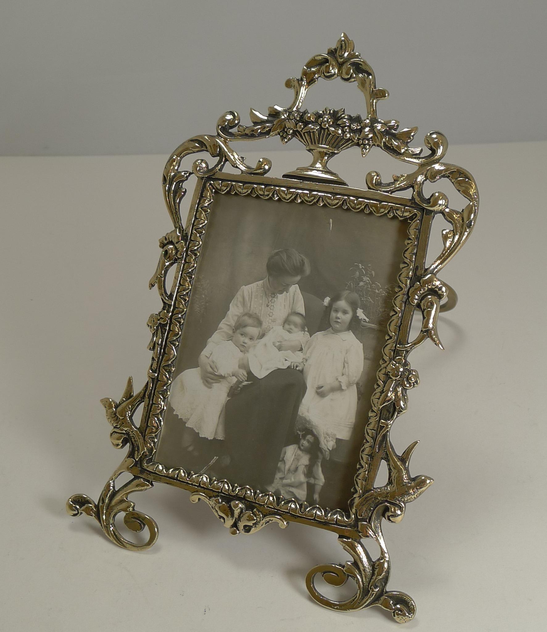Pretty as a picture, this stunning cast brass photograph frame has been professionally polished to gleam.

Standing on two scroll feet, there is a Swallow on either side just above each foot; the top has a wonderful classical urn overflowing with