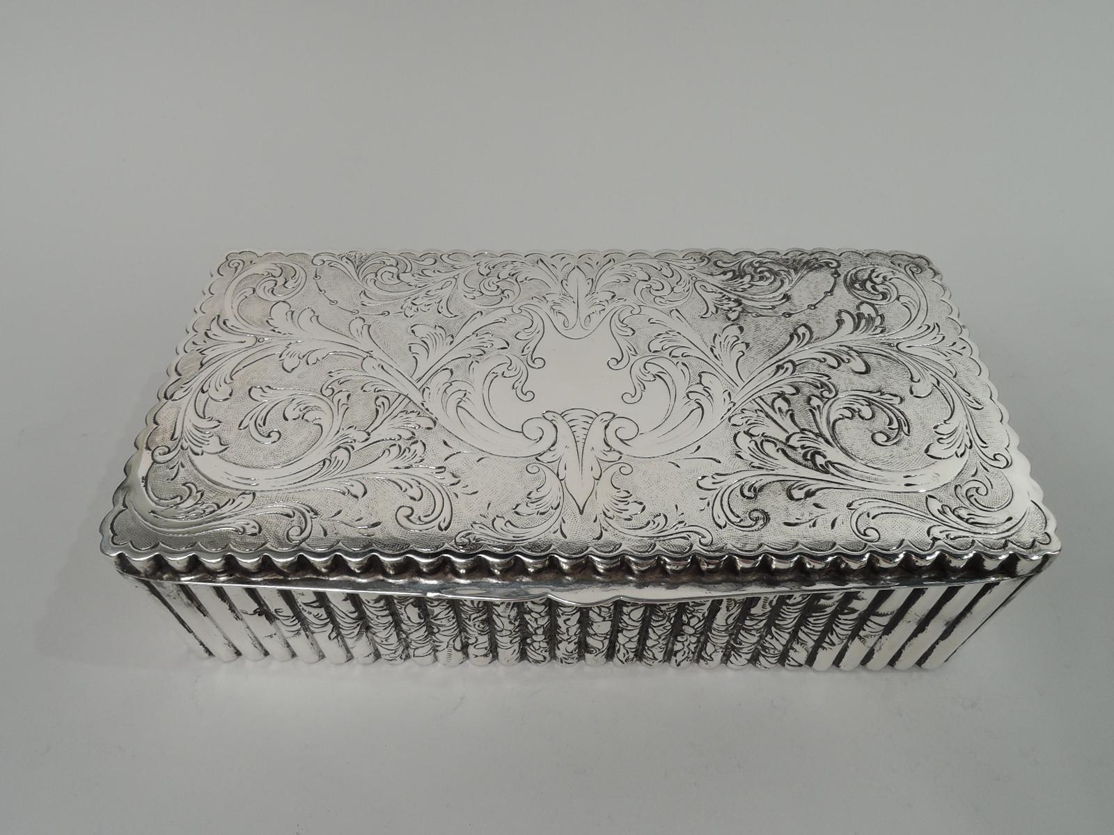 Pretty European Classical 800 silver keepsake box, ca 1940. Rectangular. Cover flat and hinged with tapering tab. Sides fluted and engraved with flowering and leafing branches. Cover top has heraldic cartouche (vacant) surrounded by leafing