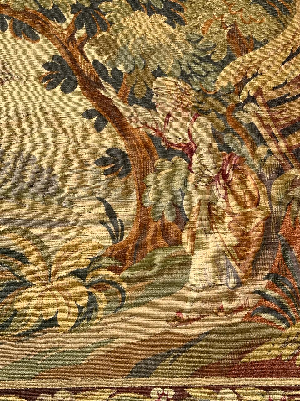 Precioso tapiz antiguo francés de Aubusson con una vista de una mujer mostrando un pájaro en la naturaleza en el bosque. Con bonitos colores naturales en tonos amarillos, verdes, rosas, naranjas y marrones, tejidos totalmente a mano en una