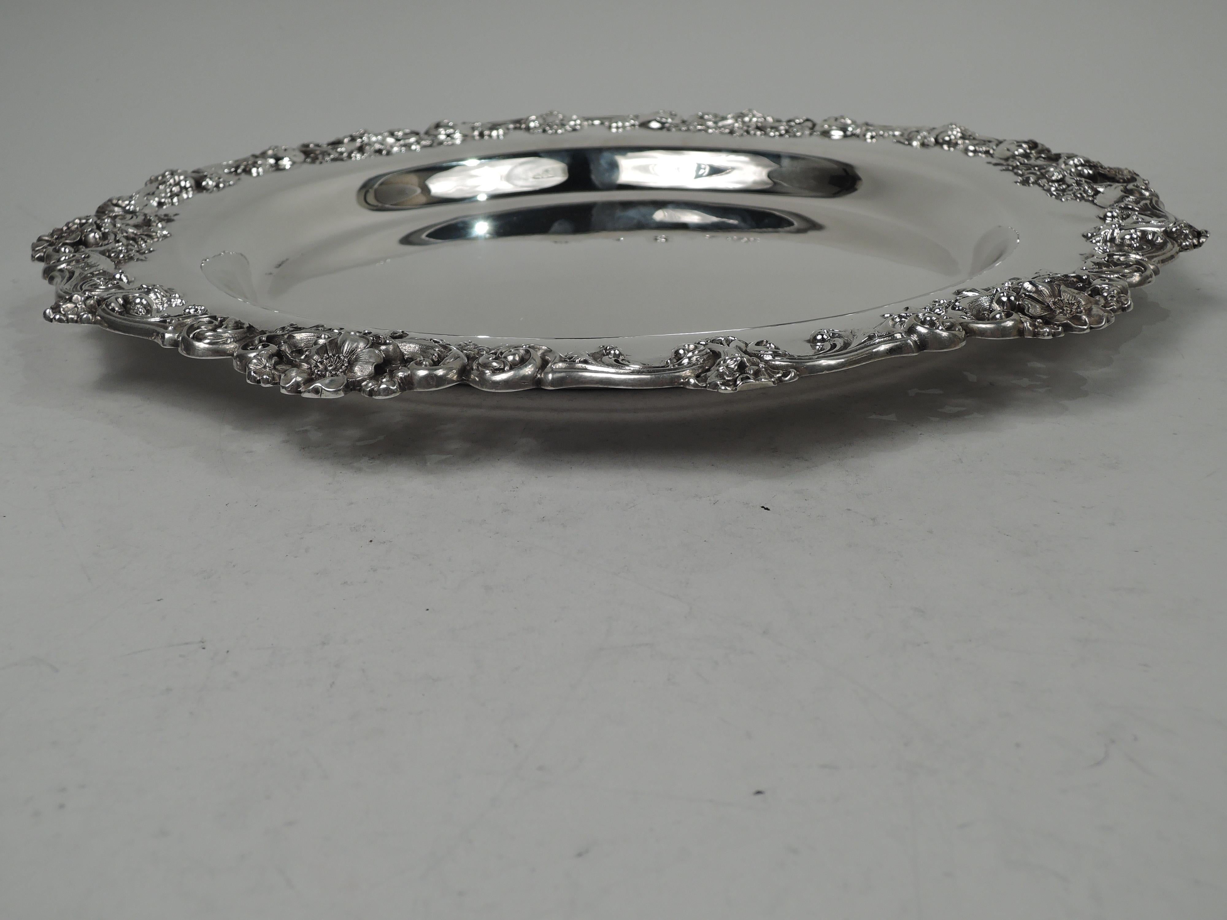 Pretty Victorian sterling silver tray. Made by Theodore B. Starr in New York, ca 1890. Round with deep well. Applied cast rim with leafing scrollwork and flowers. Fully marked including maker’s stamp and no. 3868X. Weight: 26.3 troy ounces. 