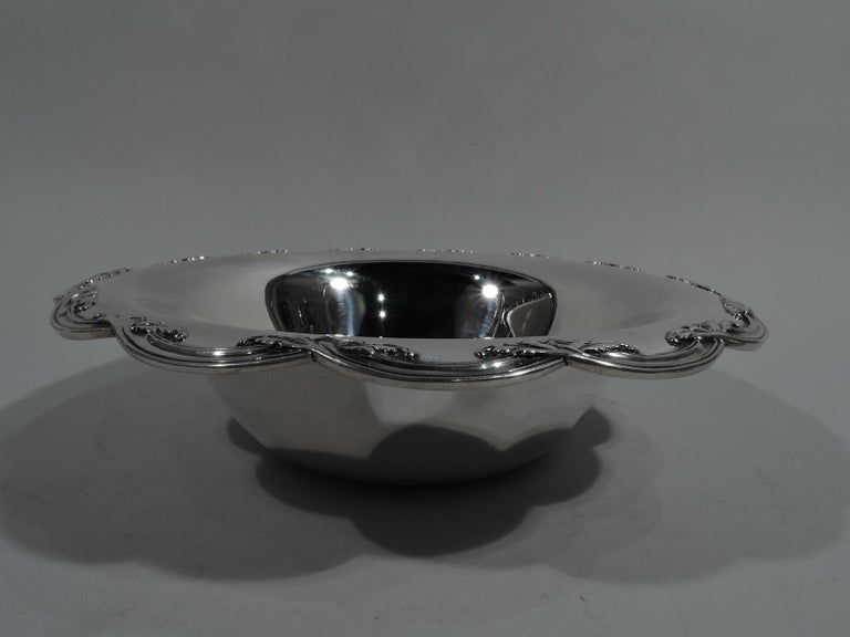 Pretty Edwardian sterling silver bowl. Made by Tiffany & Co. in New York, circa 1910. Round with tapering sides. Turned down and scalloped rim with overlapping reeded foliate C-scrolls. Fully marked including patter no. 13780K and director’s letter