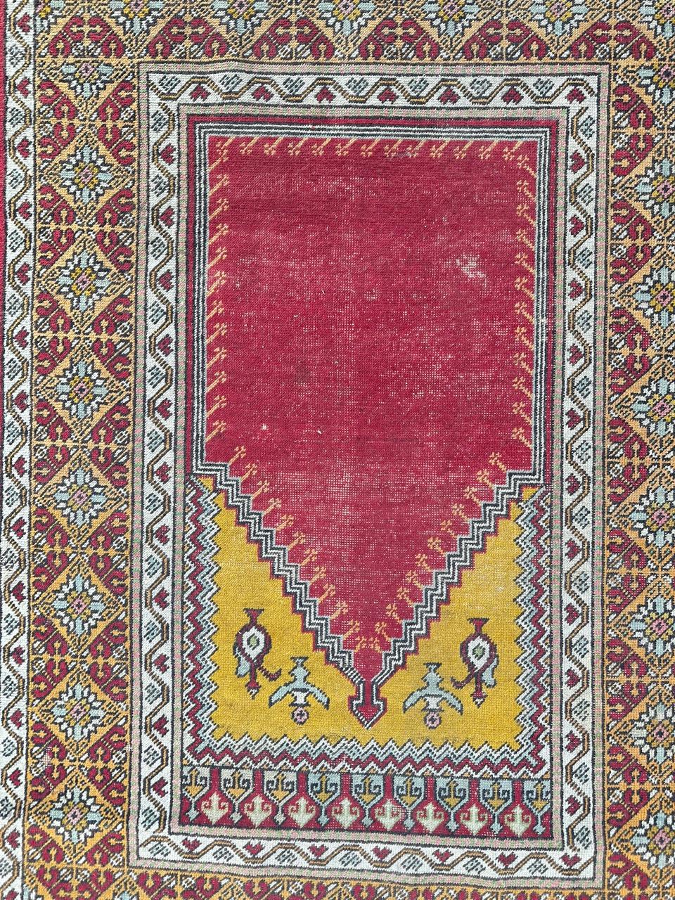beautiful antique Turkish rug from Anatolia, meticulously hand-knotted with wool velvet on a cotton foundation. This exquisite piece features uniform wear, a mesmerizing mihrab design reminiscent of mosque gates on a striking red background, two