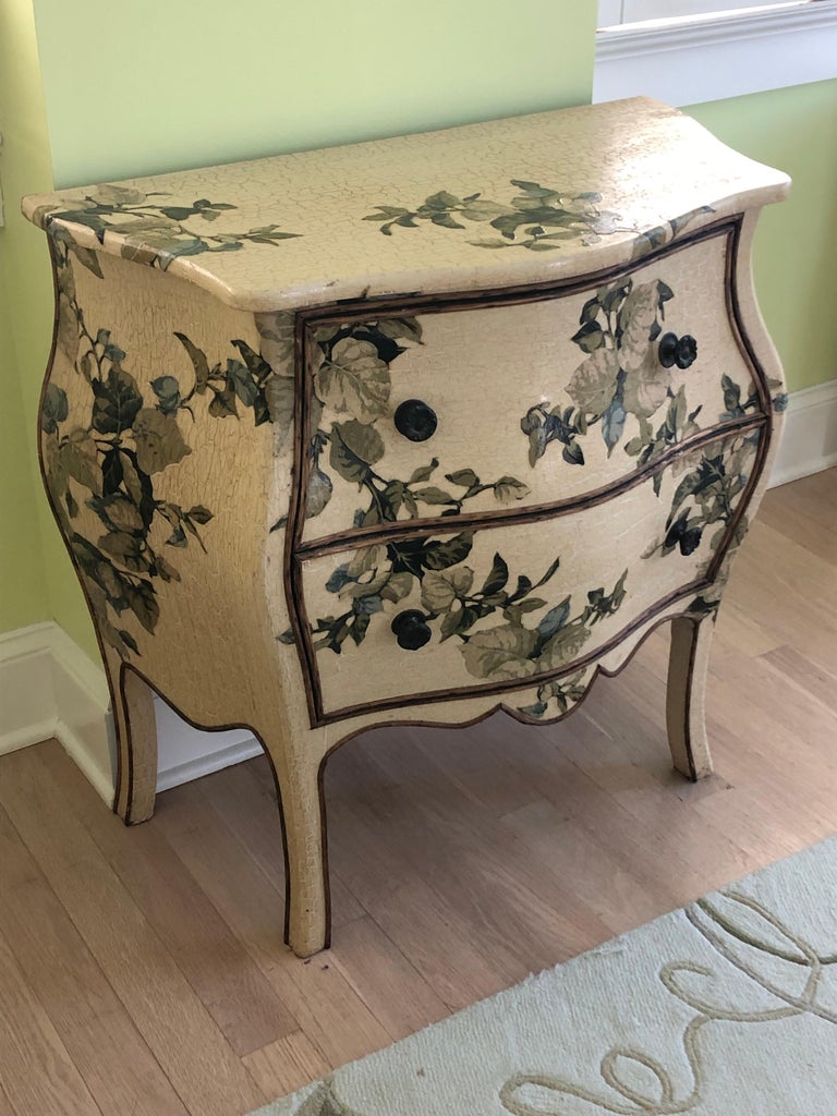 Lovely refurbished vintage bombe style chest of drawers having cream crackle painted background and decoupaged floral fabric decoration in greens, blue and taupe. 
Note: There is a matching chest that has been outfitted for tv equipment in the top