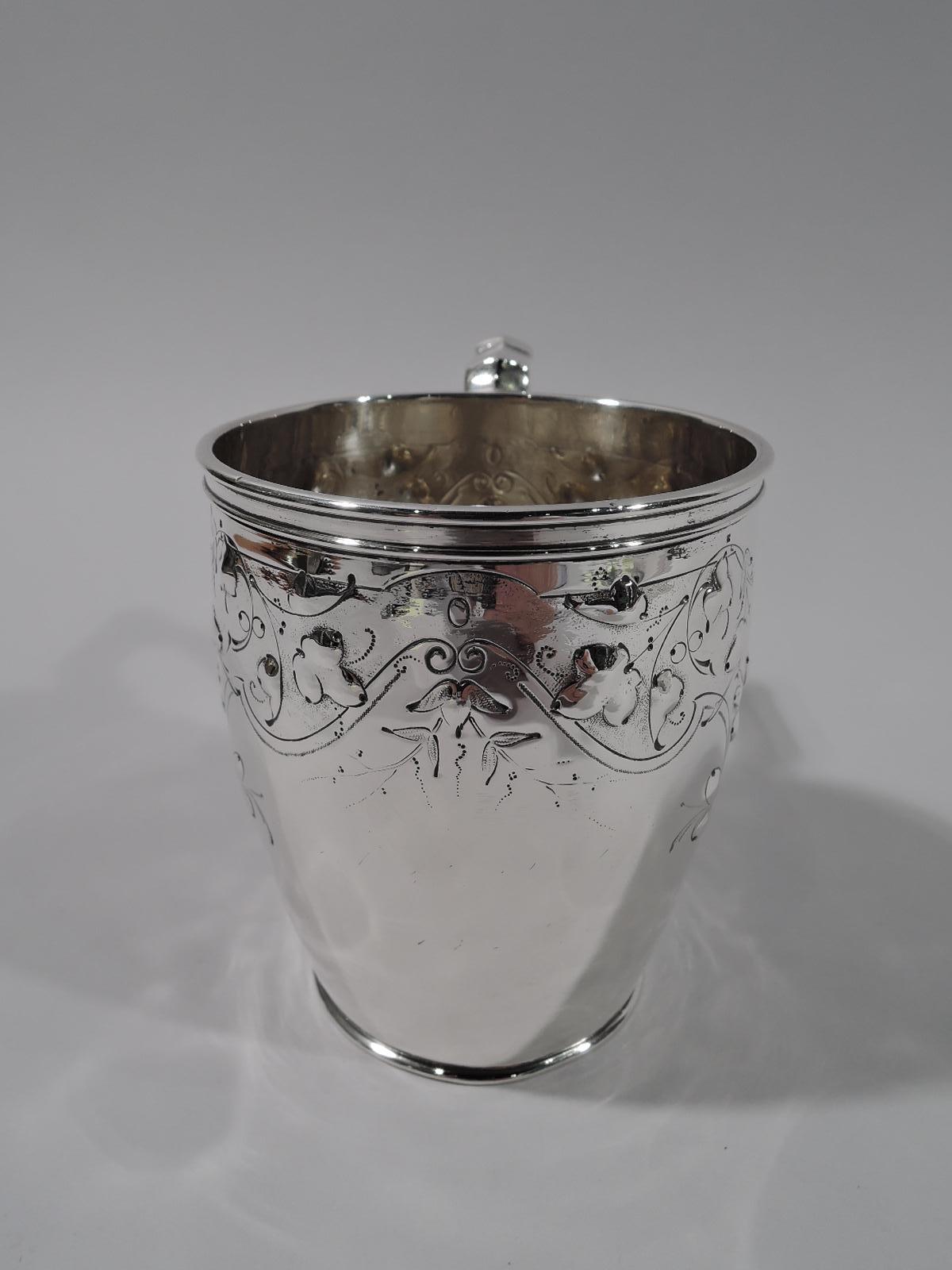 Pretty coin silver baby cup. Gently curved and tapering body and capped scroll-bracket handle. Stylized ornament with loose and scattered flowers in pendant strapwork frames. Numbered 50 with maker’s stamp for Krider & Biddle, a partnership that was