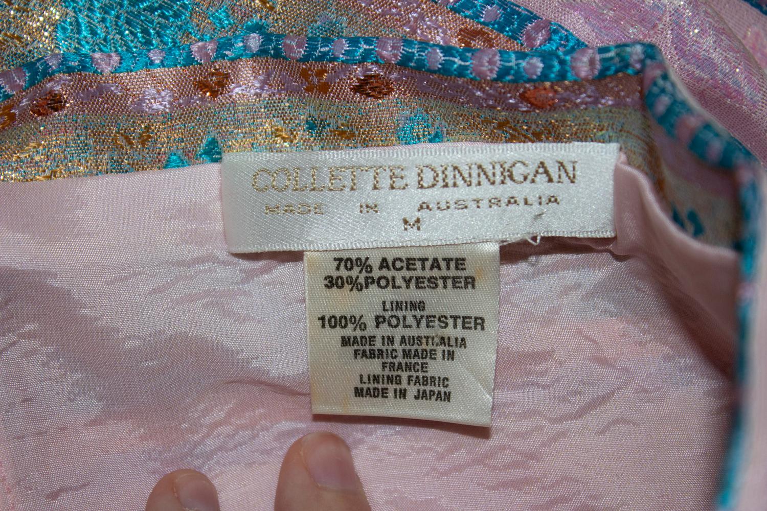 Ein sehr hübsches Cocktail- und Partykleid von Colette Dinnigan.  Das Kleid ist in einer tollen Farbkombination aus Rosa, Bronze oder Türkis in horizontalen Streifen gehalten. Das Kleid ist vorne mit Stäbchen besetzt und wird mit einem seitlichen