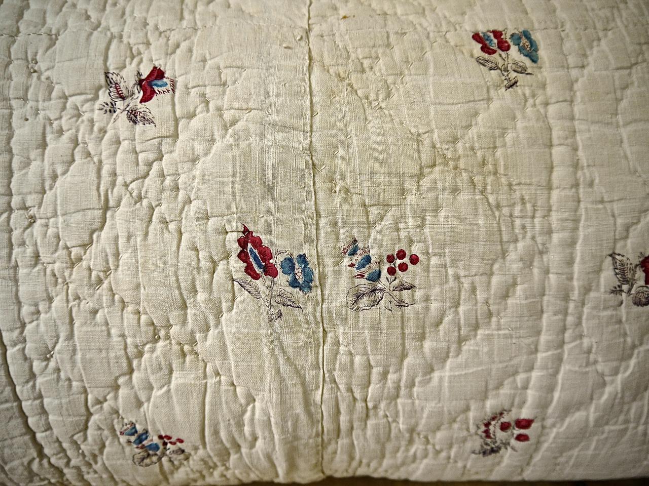 18th century French soft cotton cushion block printed with delicately drawn flower motifs. Soft raspberry pink and pale blue flowers with pale mauve leaves and stems make a fresh and charming textile. Simply quilted in a pattern of circles. In an