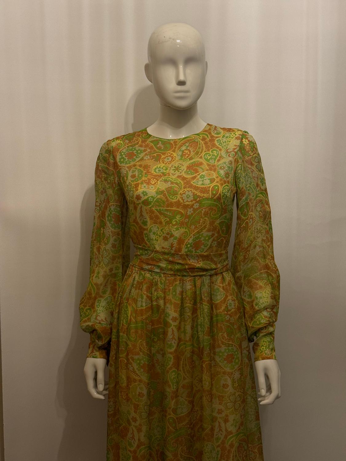 Une jolie robe vintage en tissu fleuri avec un foulard assorti. L'écharpe s'ouvre au dos par des boutons en diamant et une fermeture éclair.
Il est doté de poignets boutonnés et d'un profond volant à l'ourlet. Il y a une écharpe de marche.
Mesures :