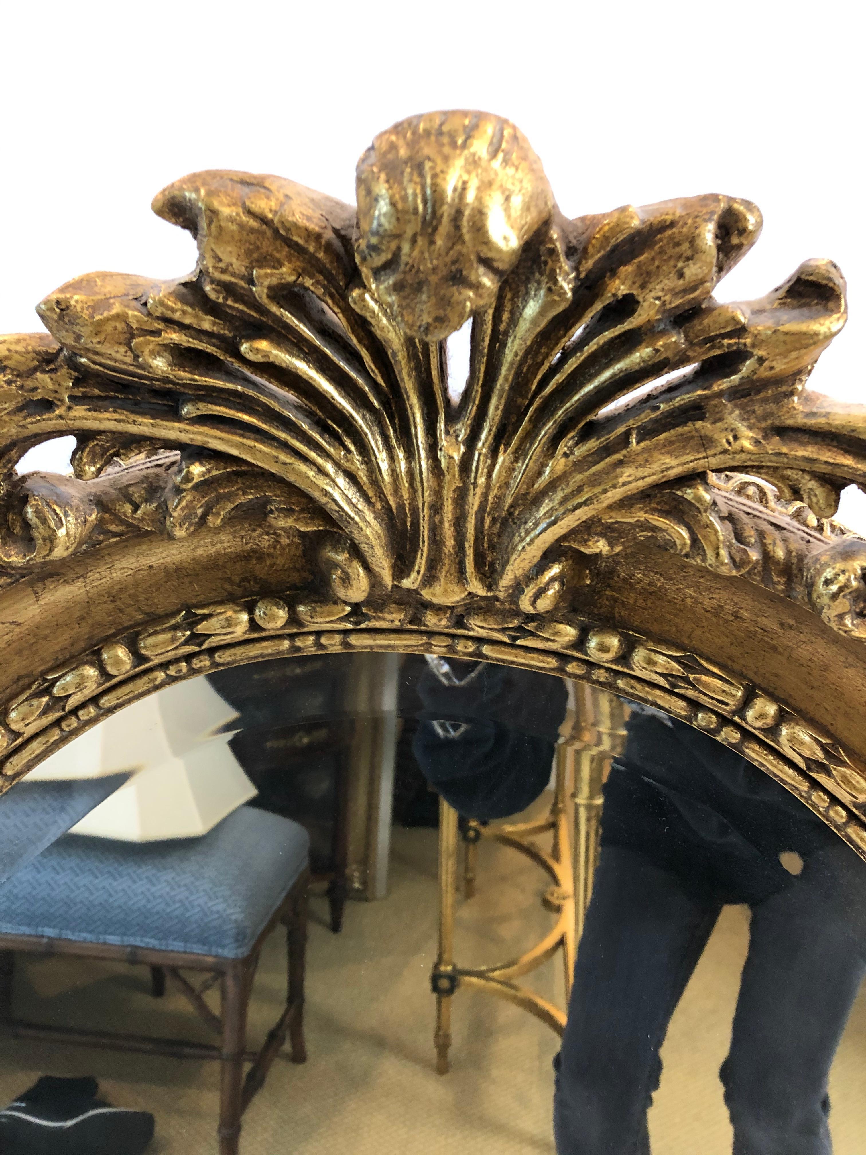 Classic French style oval mirror having carved giltwood frame with fancy shell and foliage decoration on top.
