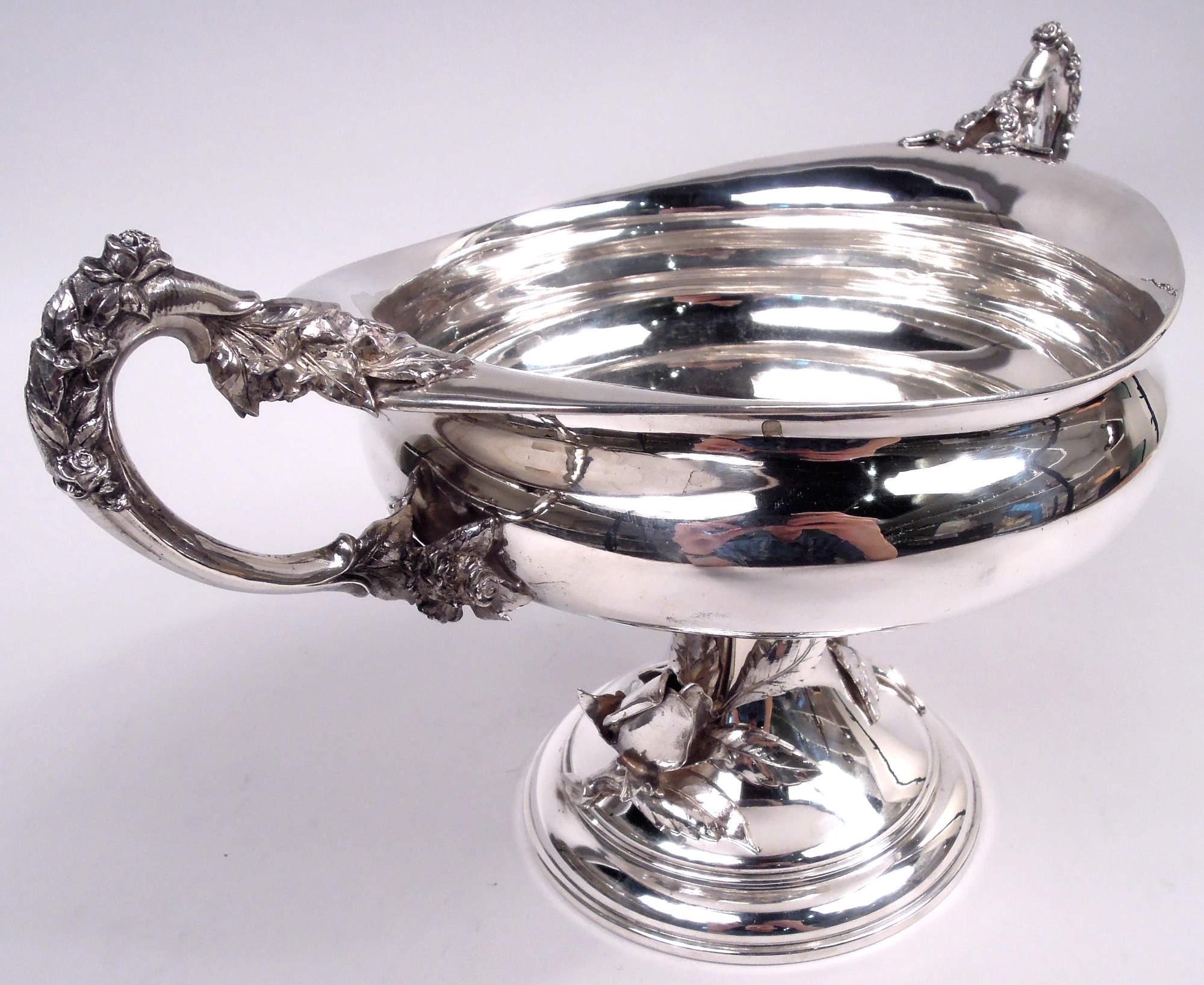 Hübsche Schale mit Fuß aus deutschem 800er Silber, um 1930. Bauchig mit gewölbtem Fuß. Seitlich hochgezogene Looping-Griffe mit gegossenem Blatt und Rosenknospen-Cap und Beschlägen. Rosenknospen mit Blättern und Stängeln, die an der Unterlage