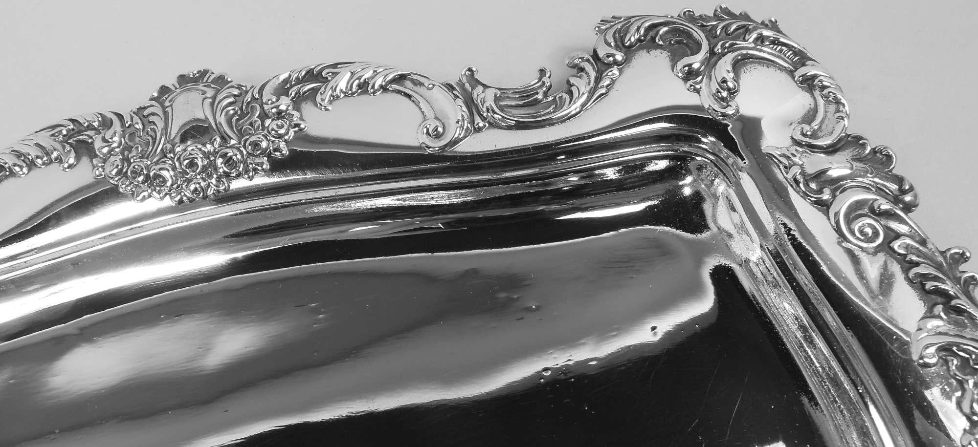 Pretty Victorian Classical sterling silver tray. Made by Meriden Britannia (part of International) in Connecticut, ca 1900. Shaped rectangular well and everted shoulder; scrolled rim applied with leafing scrolls and heraldic shield frames (vacant)
