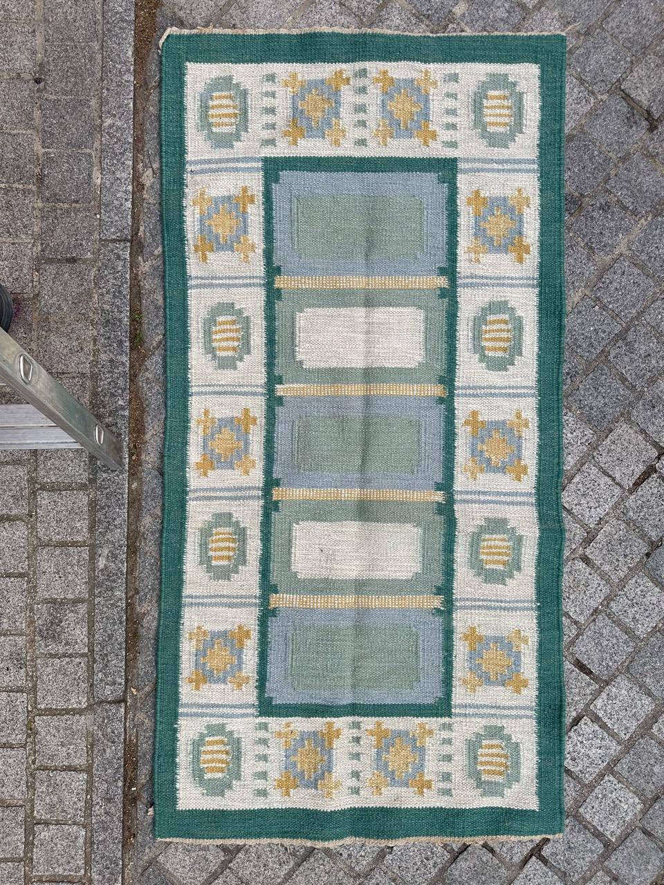 Ein charmanter skandinavischer Flachgewebe-Teppich im Vintage-Stil mit einem atemberaubenden geometrischen Muster im Art-Déco-Stil in weichen, hellen Farben. Dieses exquisite Stück ist vollständig aus Wolle auf Baumwollbasis handgewebt. Das Feld des