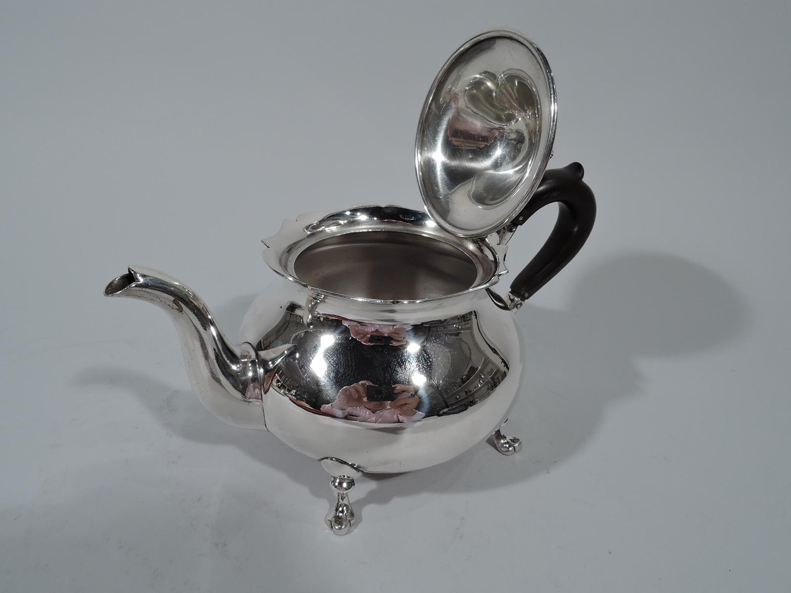 Pretty colonial revival sterling silver teapot in Jack Shepard pattern. Made by Lunt in Greenfield, Mass. Bellied with s-scroll spout and capped high-looping stained-wood handle. Flared and scrolled rim. Hinged and domed cover with ornamental