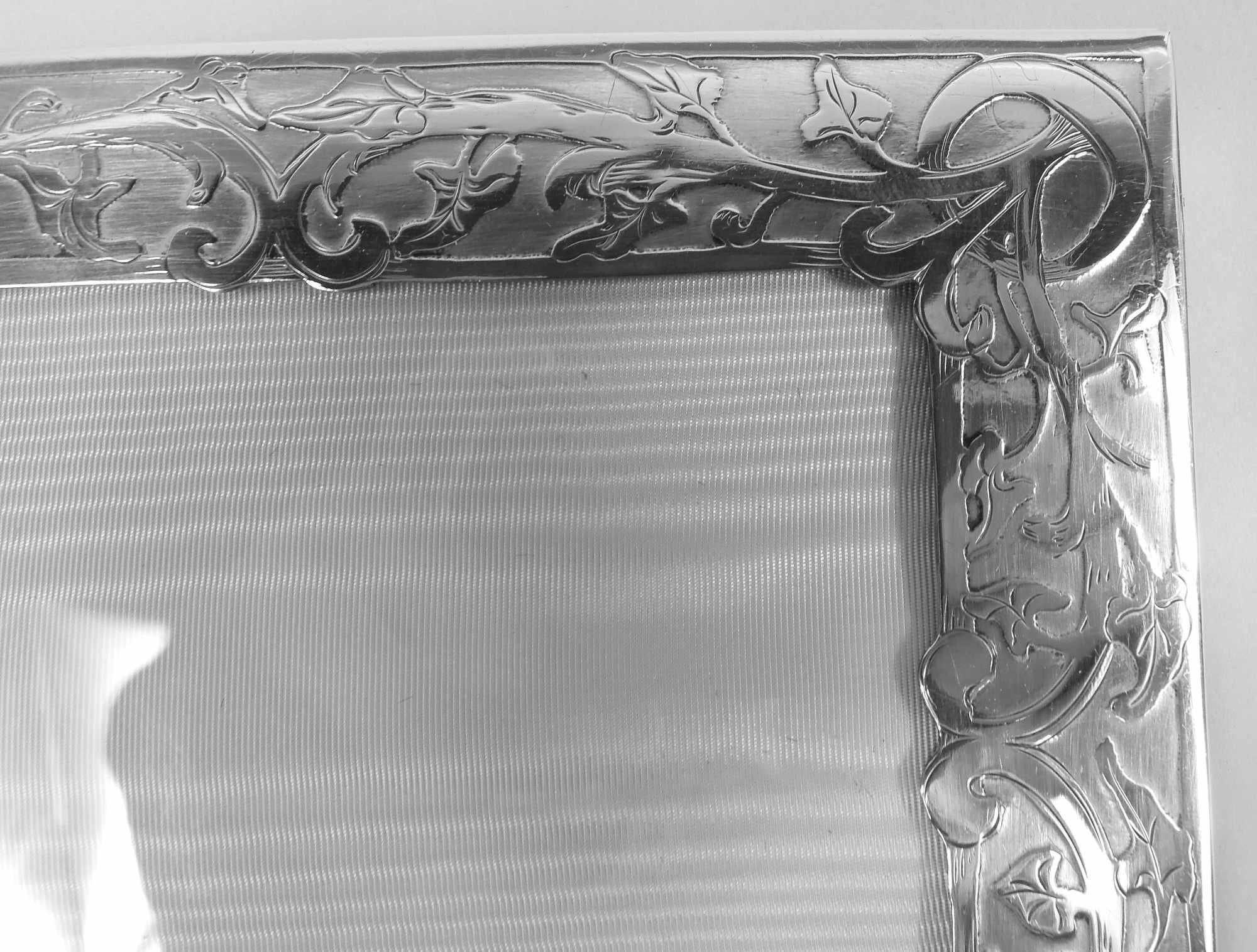 Pretty Art Nouveau sterling silver picture frame. Made by Meriden Britannia (part of International) in Connecticut, ca 1900. Rectangular window in flat surround with irregular interior rim. On front acid-etched wraparound scrolling leafing branch