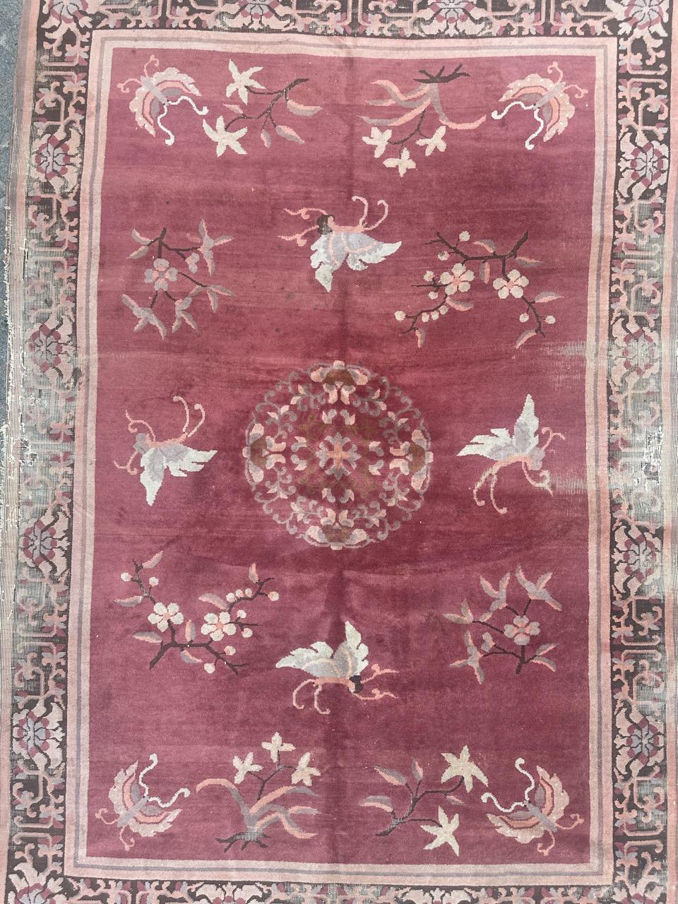 Beautiful mid 20th century Chinese rug with a nice of flowers and butterflies on the pink background in the field, surrounded by stylised flowers on a brown background in the borders, entirely hand knotted with wool on cotton foundation. Wears and