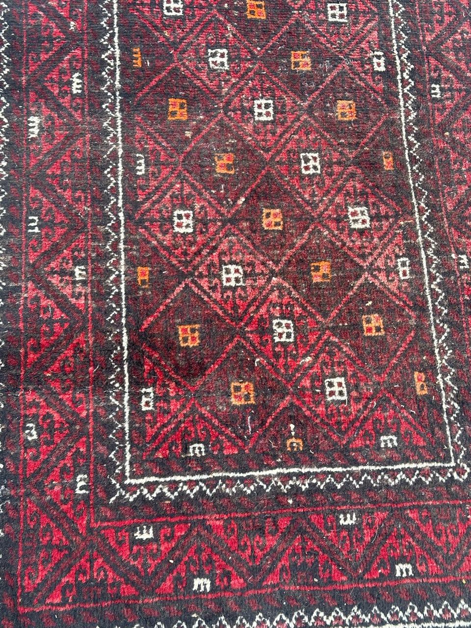 Beau tapis turkmène Baluch du milieu du siècle avec de beaux motifs géométriques et tribaux et de belles couleurs avec du rouge, du violet, de l'orange, du noir et du blanc, entièrement noué à la main avec de la laine sur une base de coton. 
Usures