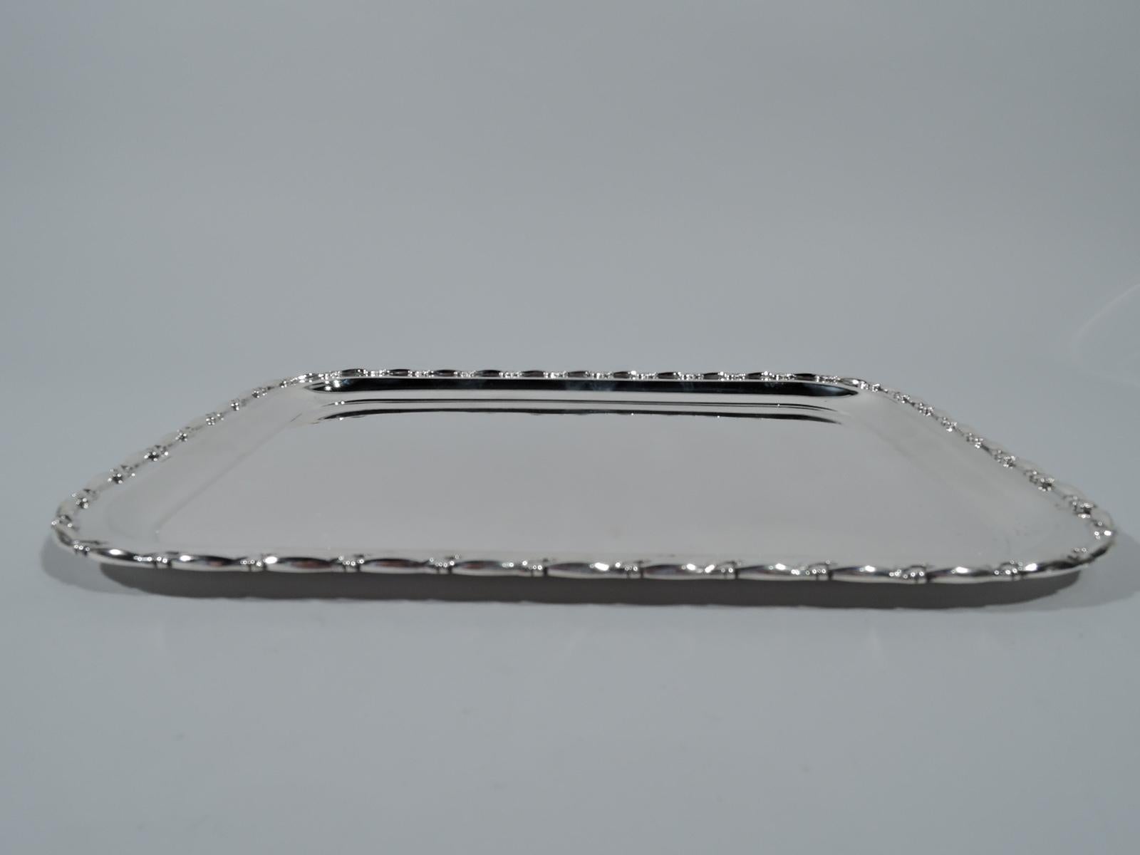 Pretty Midcentury sterling silver tray. Made by Reed & Barton in Taunton, Mass. Rectangular well with curved corners and flat rim with applied leaf ornament. Hallmark includes no. 388. Weight: 19.3 troy ounces.