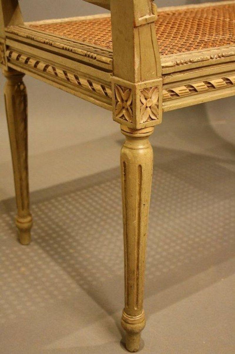 SN704 early 20th century, Continental, painted stool/seat, having cane work to seat and ends, carving decoration to all edges and standing on slim turned and reeded leg with floral motif to top, in excellent original condition. c1900
H28