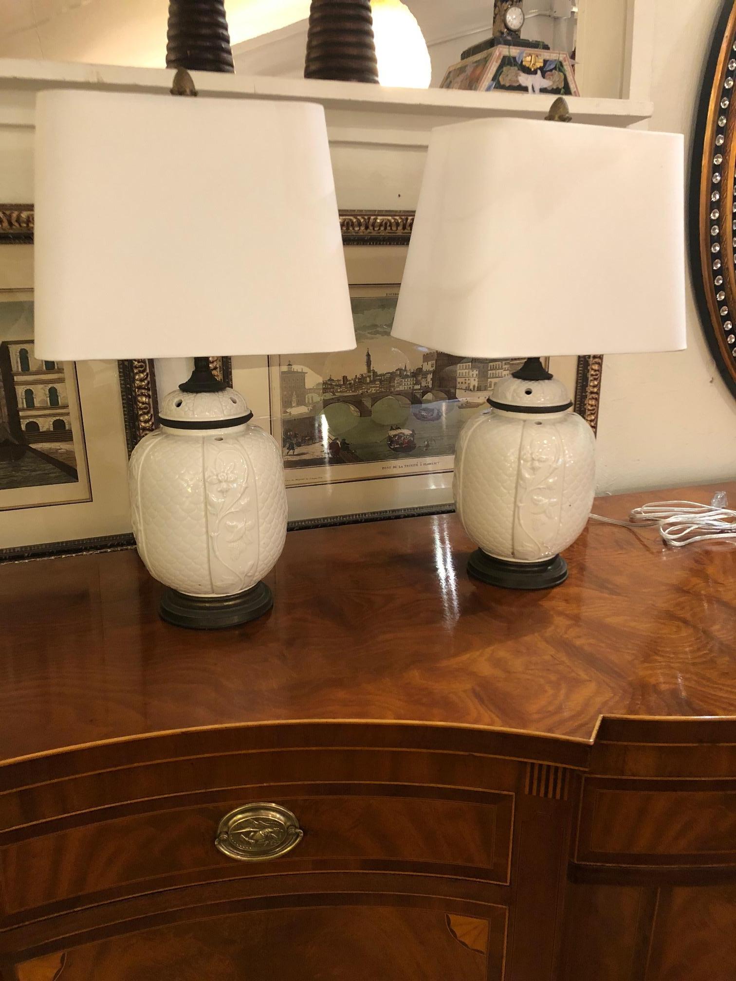 Elegant pair of vintage jar shaped ceramic blanc de chine lamps having lovely raised patterns and wooden bases. New custom shades included.