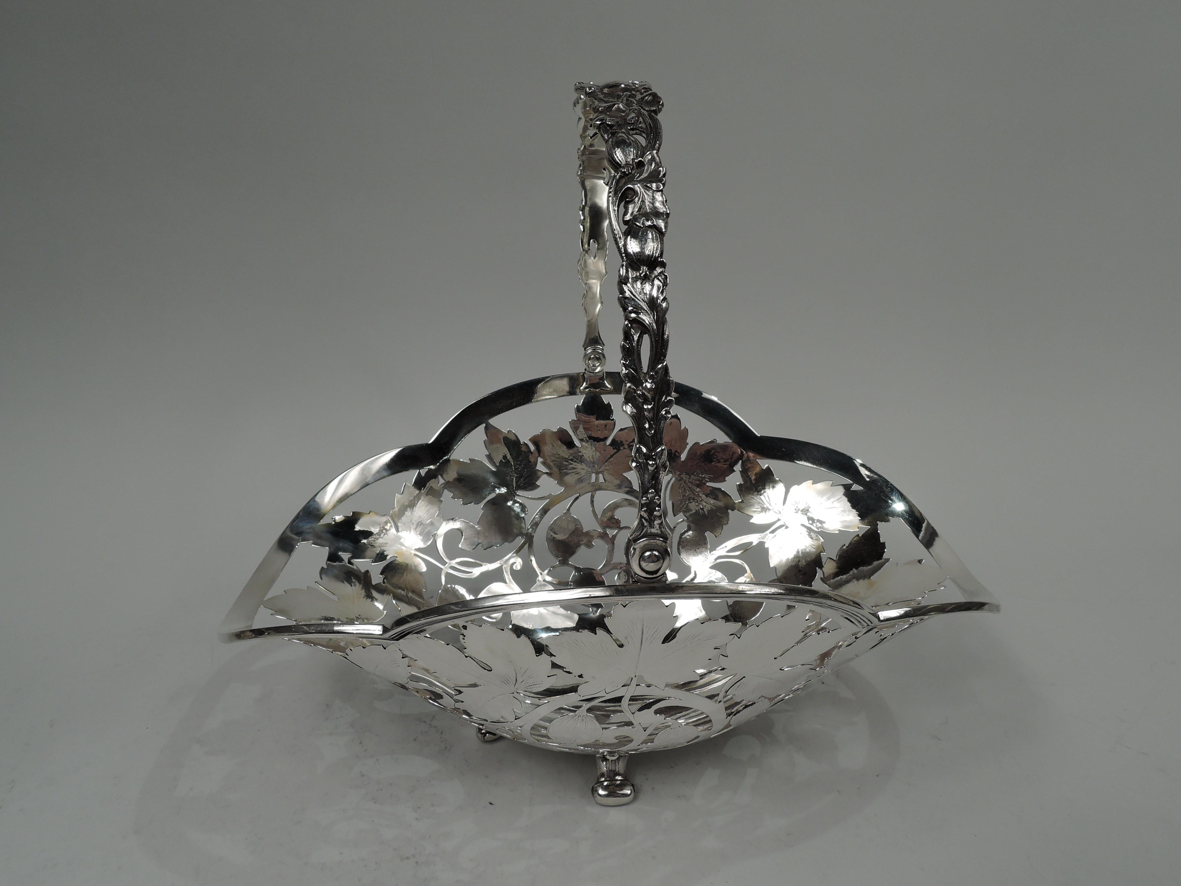 Art Nouveau sterling silver basket. Made by Tiffany & Co. in New York, ca 1910. Deep and ovoid with reeded and lobed rim. Cast and open fruiting and leafing vine swing handle with central oval cartouche (vacant). Sides open and engraved with same.