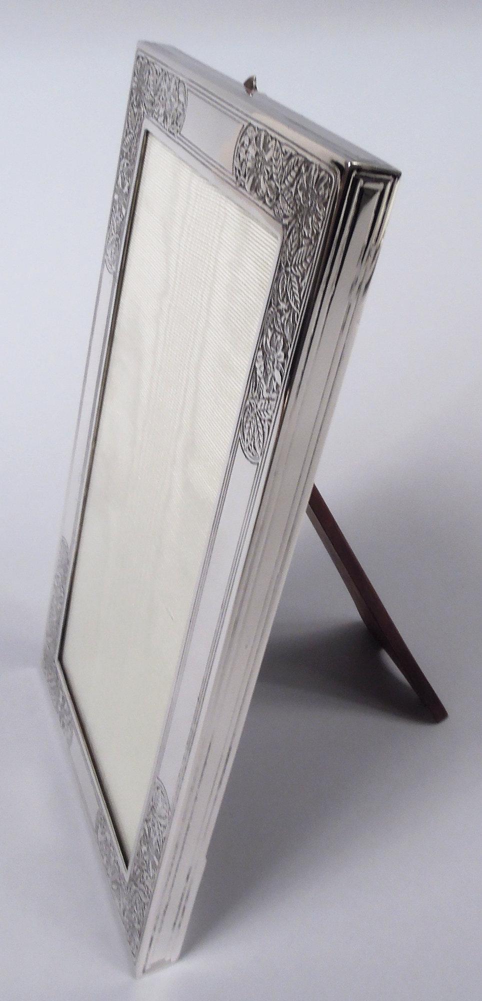 Marco Art Nouveau de plata de ley. Fabricado por Tiffany & Co. en Nueva York, hacia 1910. Ventana rectangular en marco plano. En las esquinas, frentes y flores grabados al ácido; los lados tienen bordes rectilíneos incisos. Fresca y bonita, con