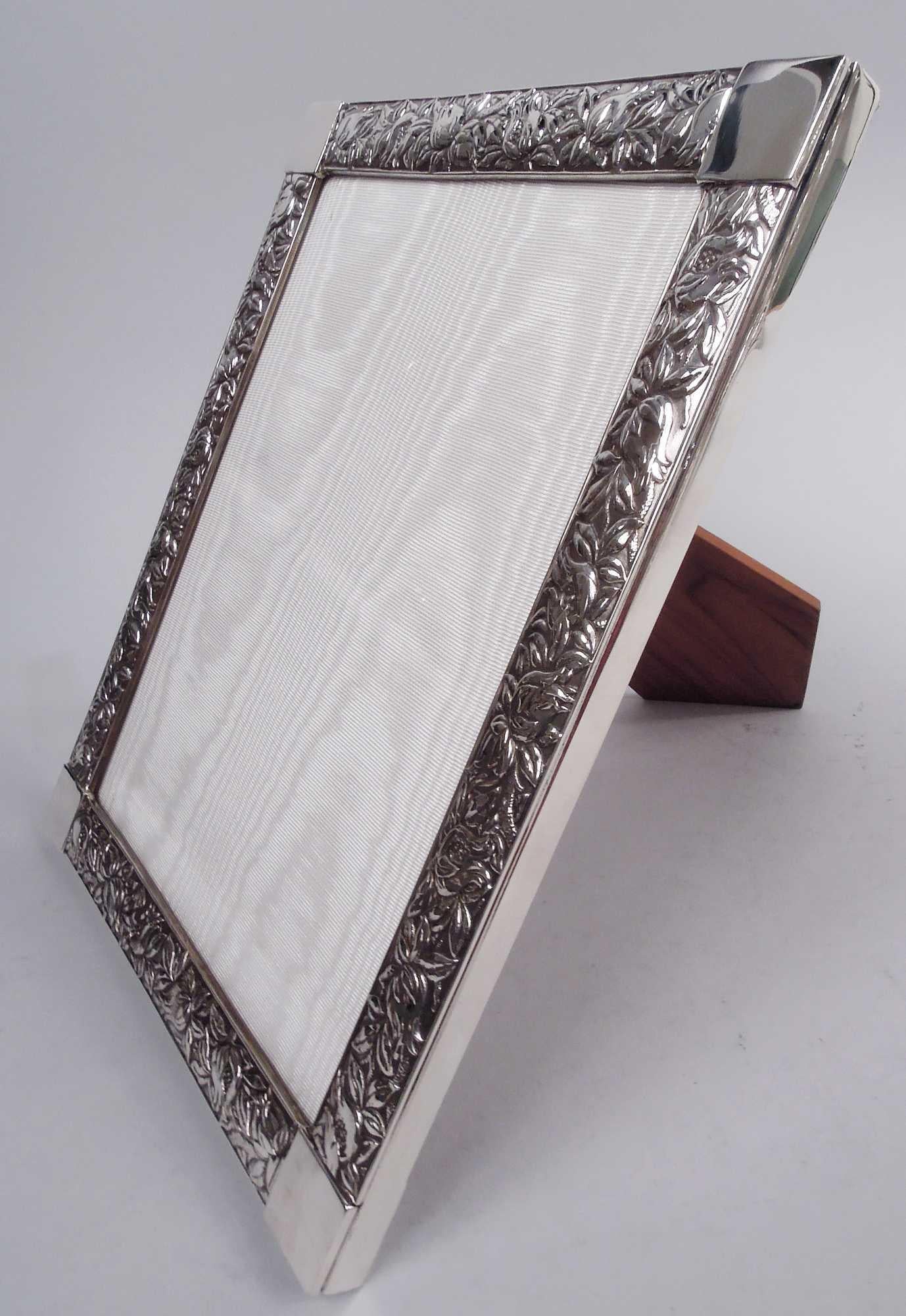 Art Nouveau sterling silver picture frame. Made by Tiffany & Co. in New York. Rectangular window in cast surround with overlapping leaves and pomegranates. Applied plain corner squares (vacant). With glass, silk lining, and wood laminate back and