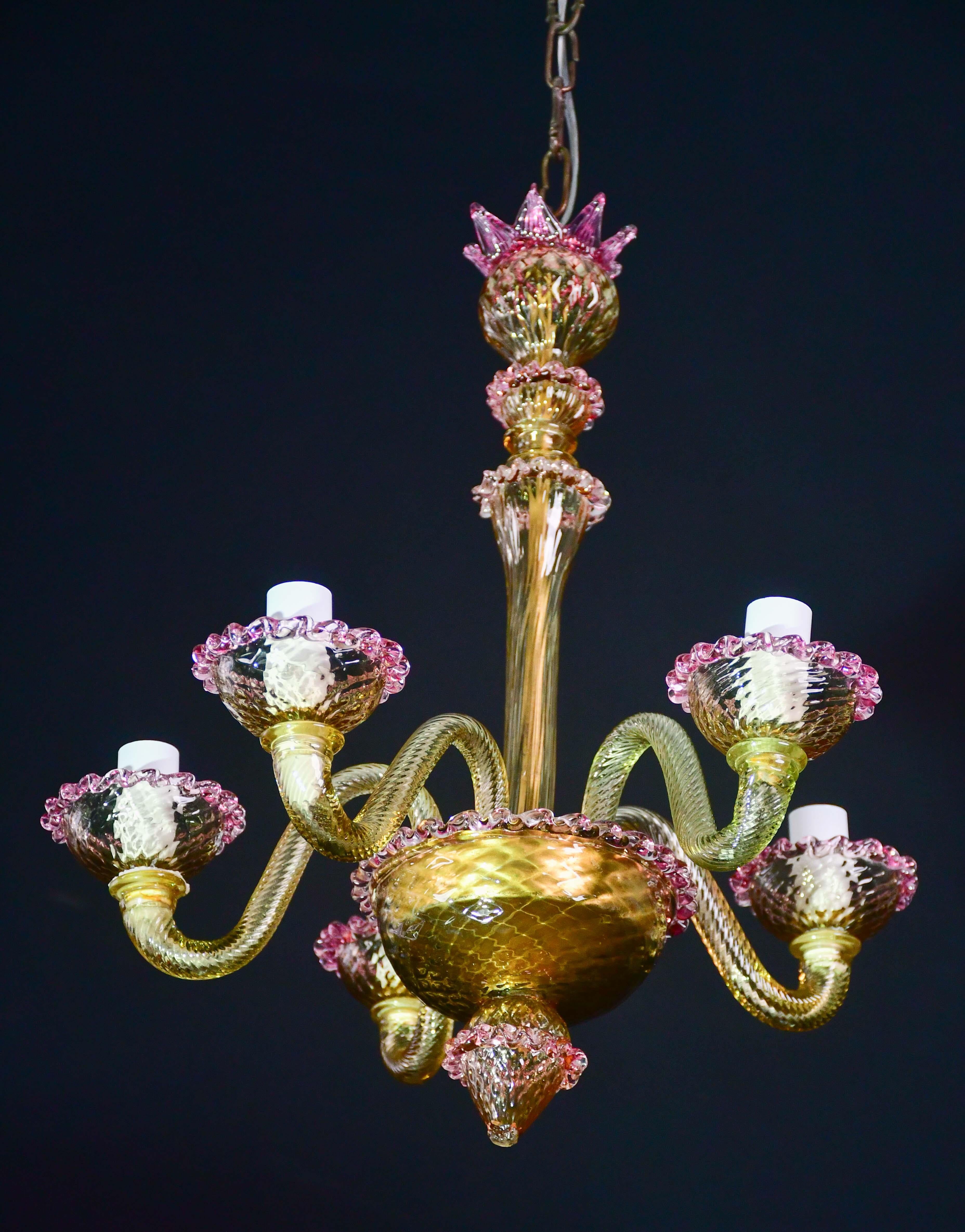 Hübscher Murano-Kronleuchter, typisch klassische venezianische Farbe rosa und gold.

Der Kronleuchter hat 5 Arme, an denen 5 e14-Lichtpunkte nach europäischem Standard angebracht sind.

Die Höhe beträgt 95 Zentimeter mit Kette, 50 Zentimeter ohne