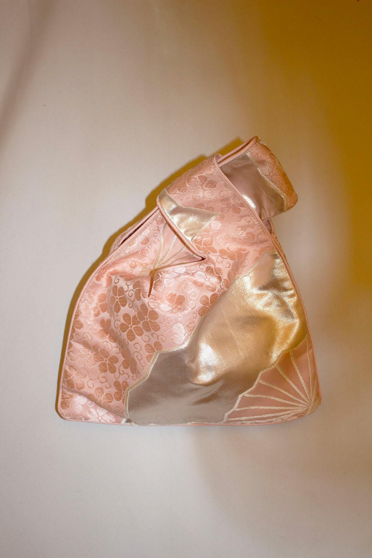 Eine hübsche und einfach zu handhabende Vintage-Handtasche aus seltenen alten Obi-Gürteln. Die Tasche ist in einem rosa, silbernen und floralen Design gehalten und die Henkel lassen sich einfach ineinander stecken. Die Tasche ist vollständig