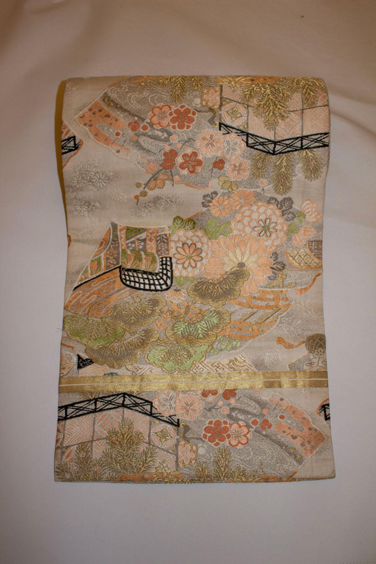 A pretty vintage Maru Obi Belt . These belts are the most formal of obi belts. They  have a pattern on both sides, in this case a floral scene in green, peach and black.  They would mostly have been worn by geisha and mariko.
Measurements: Height 12