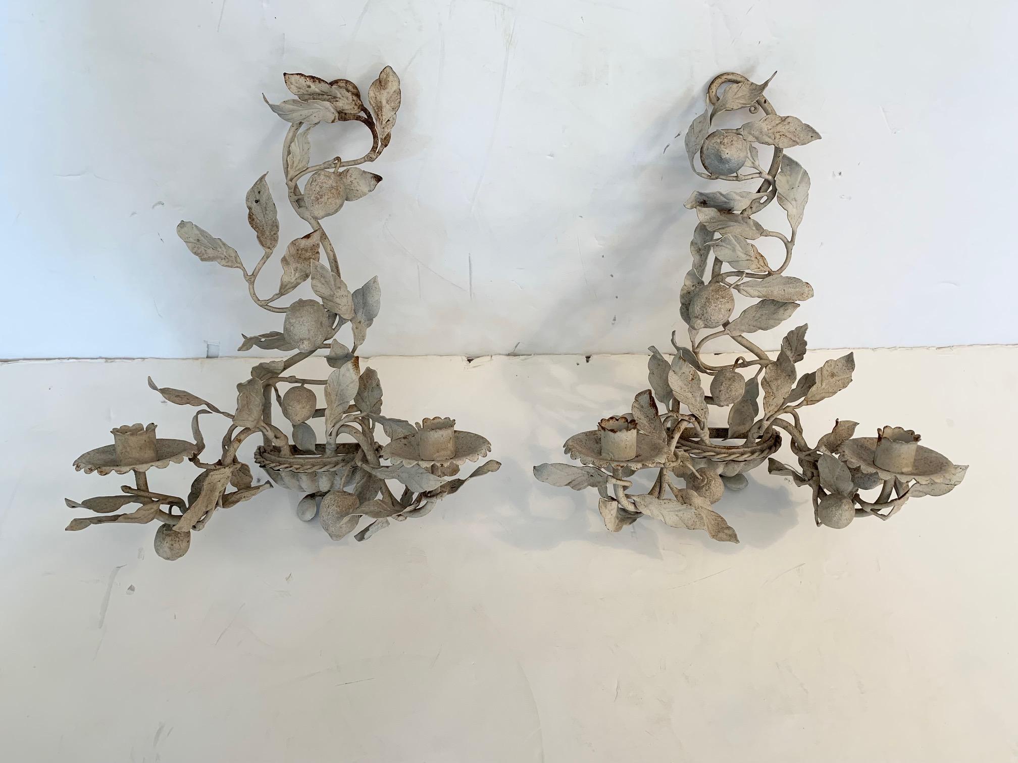 Pretty pair of vintage painted antique white tole and iron wall sconces having two arms each with candle holders and artfully placed leaf decoration.