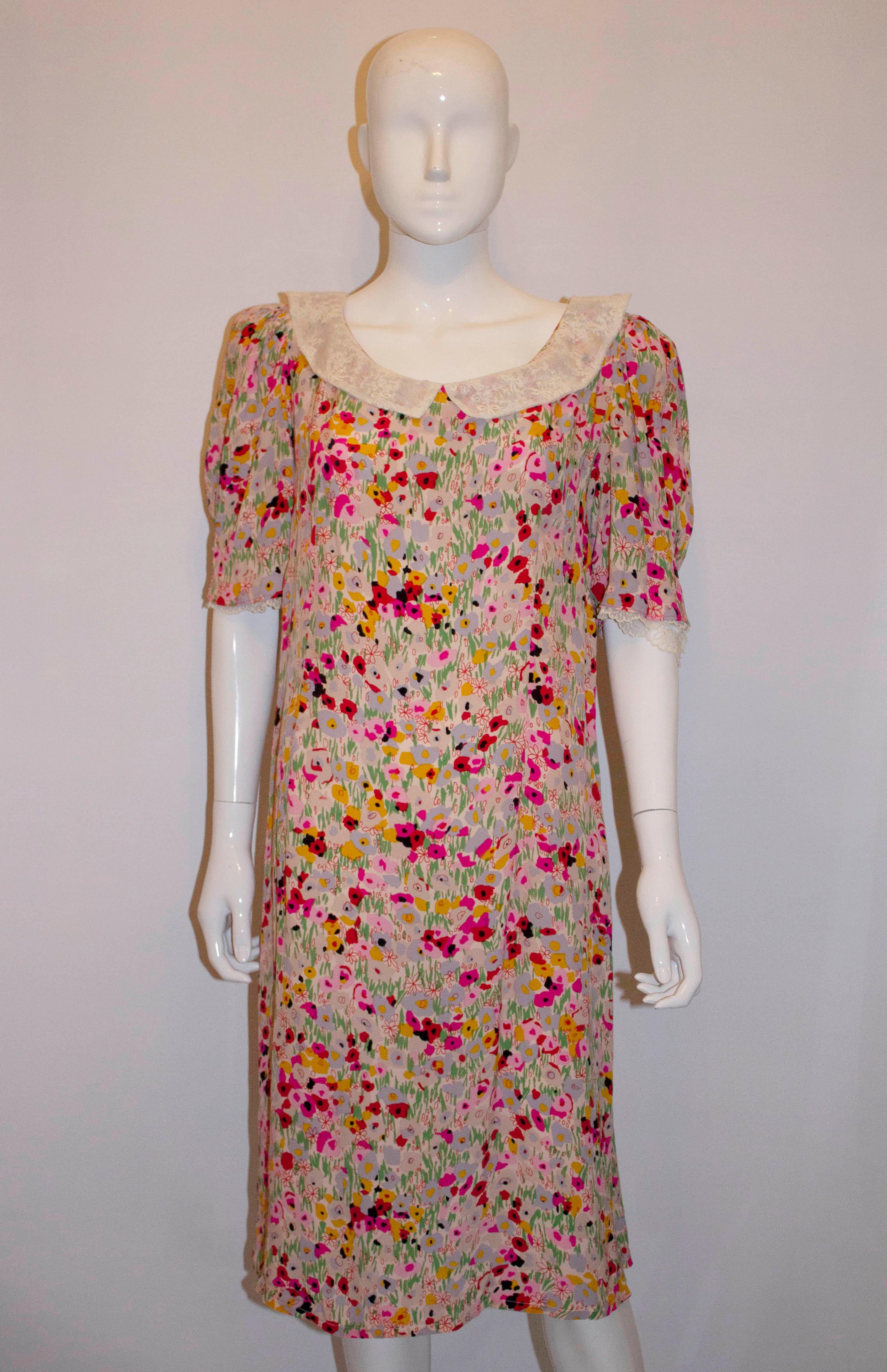 A vintage dress in a pretty print with lace detail,  The dress has a lace trimmed collar and sleaves and a central back zip opening. It is unlined. Measurements: Bust up to 40'', length 44''.