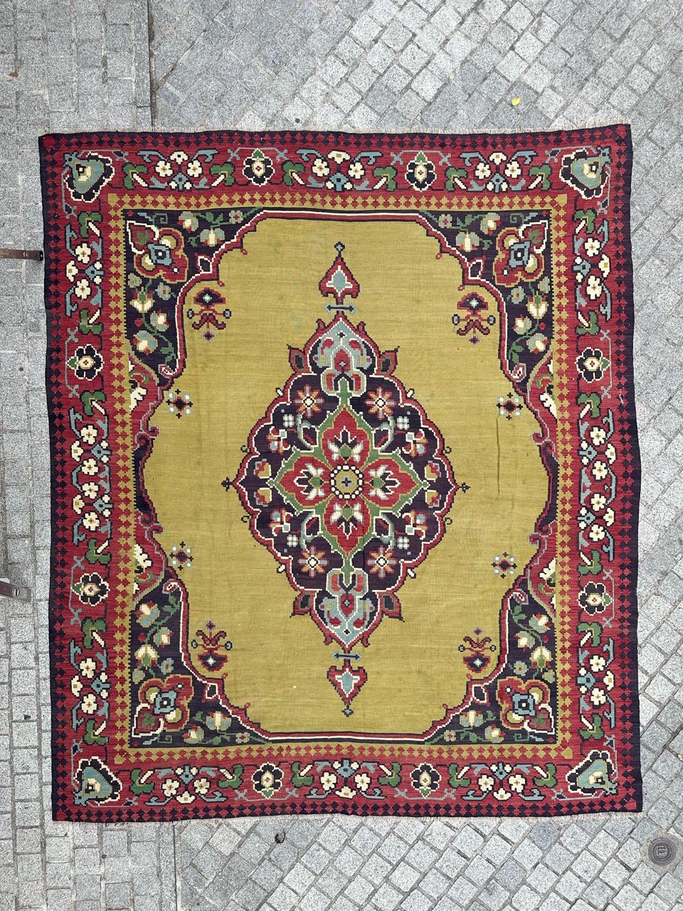  A beautiful mid-century large Kilim featuring a stunning Turkish Oushak rug design with vibrant colors. This piece is entirely handwoven with wool on a wool foundation. It showcases a lovely yellow background with a large medallion. The central