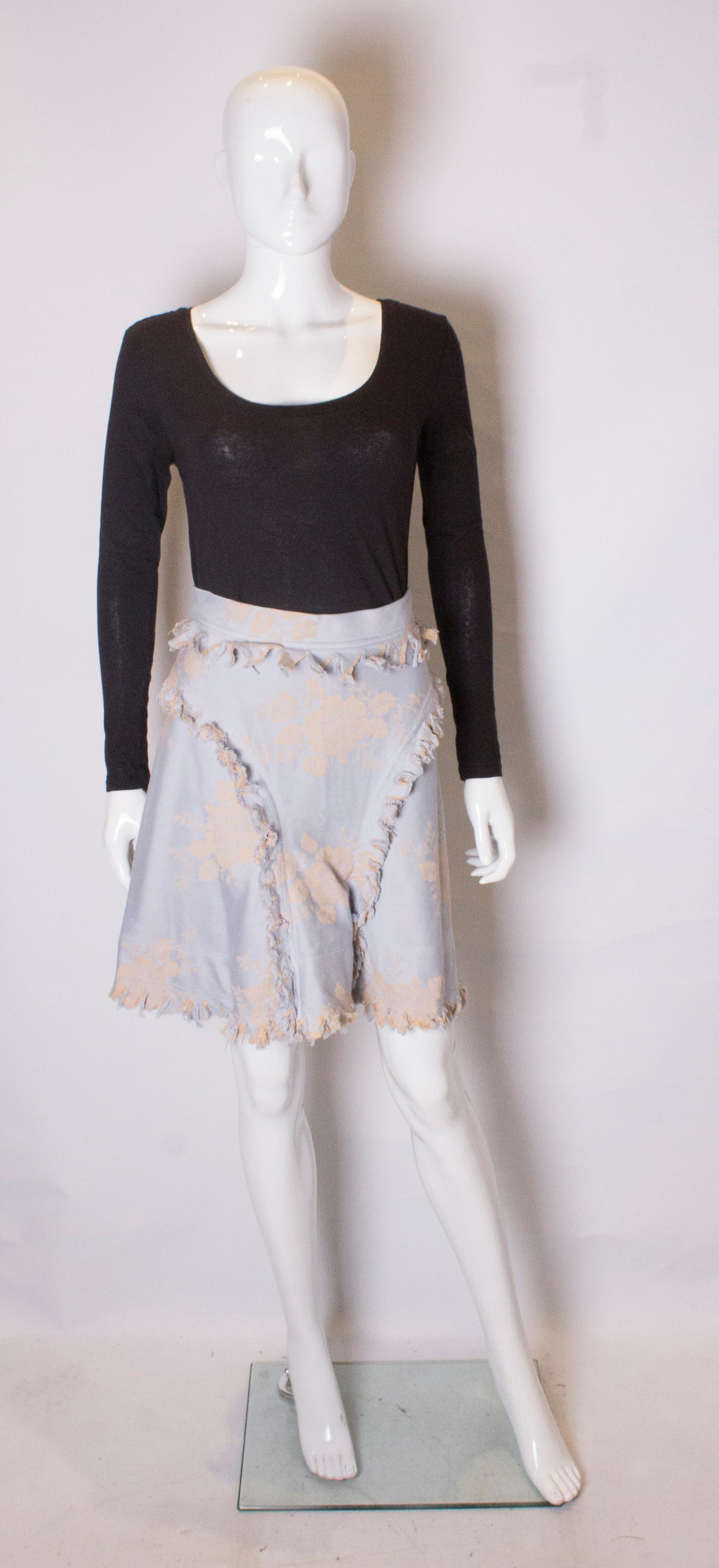 A pretty skirt by Vivienne Westwood , Gold label. The skirt is made of cotton, in a pretty sky blue and gold print.It has decorative fringing on the front and back and a concealed zip opening.
