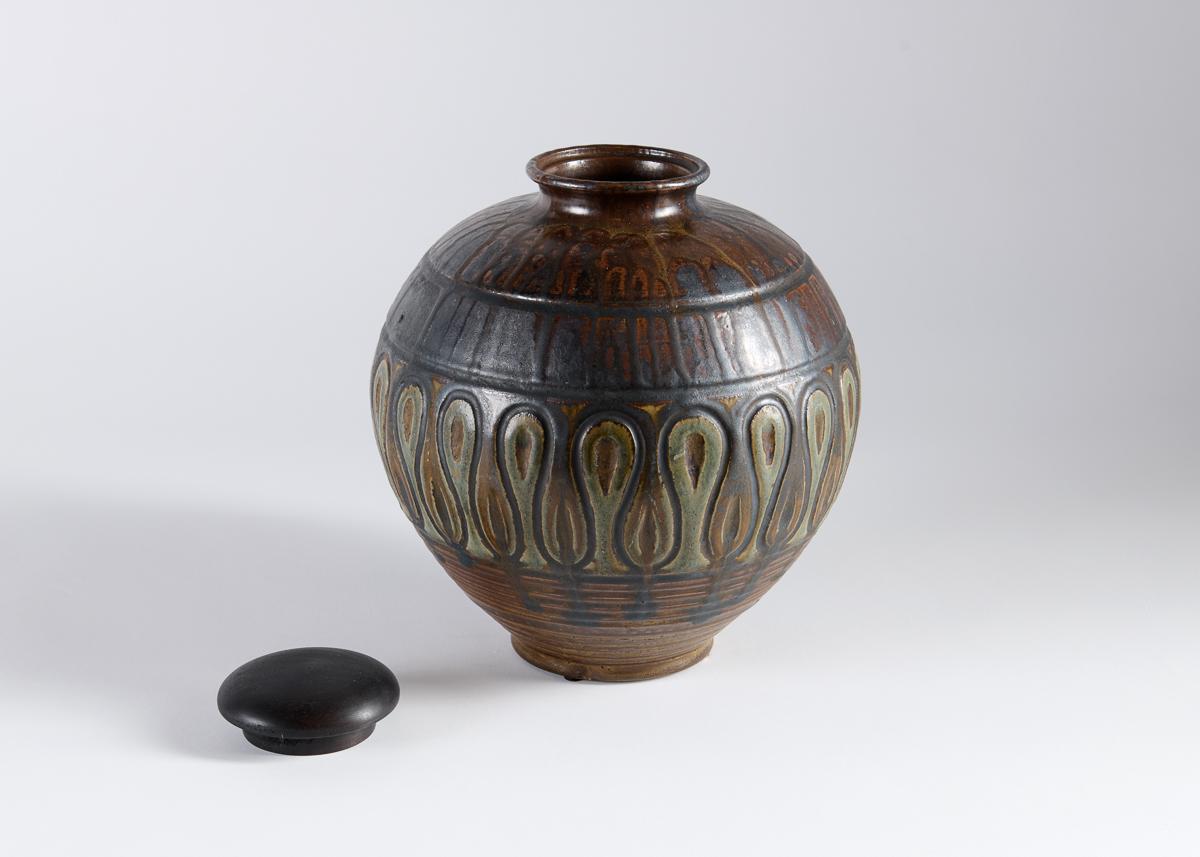 Ce vase Art nouveau de forme ovale est décoré d'un motif serpentin en boucle dans des tons sombres et sourds de brun et de vert. Signé.
