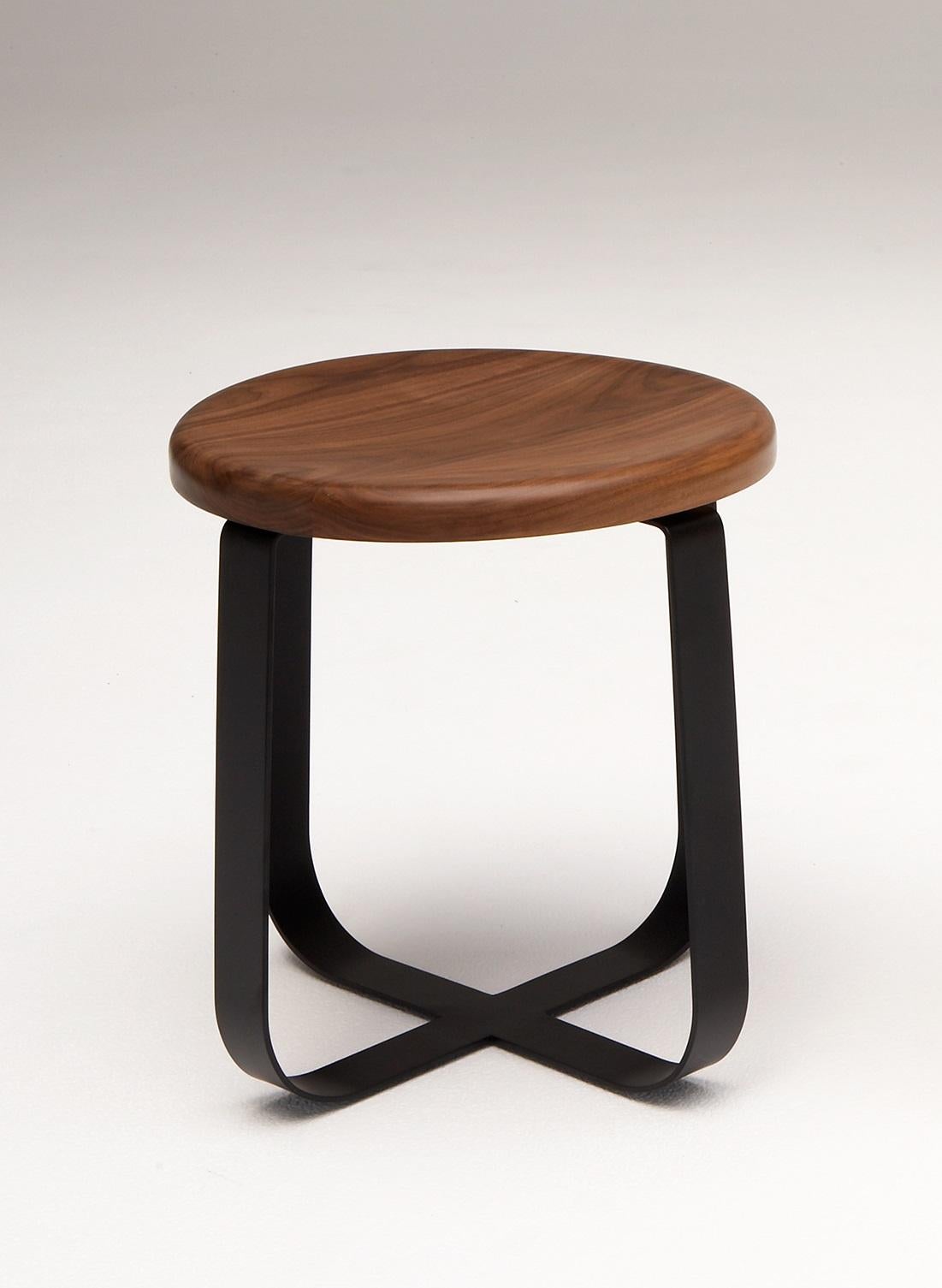 Primi Low Stool by Phase Design
Dimensions: Ø 48.3 x H 44.5 cm. 
Materials: Powder-coated steel and walnut.

Solid steel flat bar available in a flat black or white powder coat finish with CNC cut walnut, white ash, or upholstered top. Powder coat