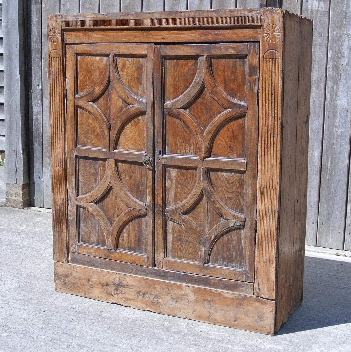 A most unusual and characterful solid elm cupboard, a primitive cottage piece made in around 1750 and probably Irish.

With substantial fielded panel and framed doors with applied Elm mouldings which create a lozenge shape to each panel. The flanks