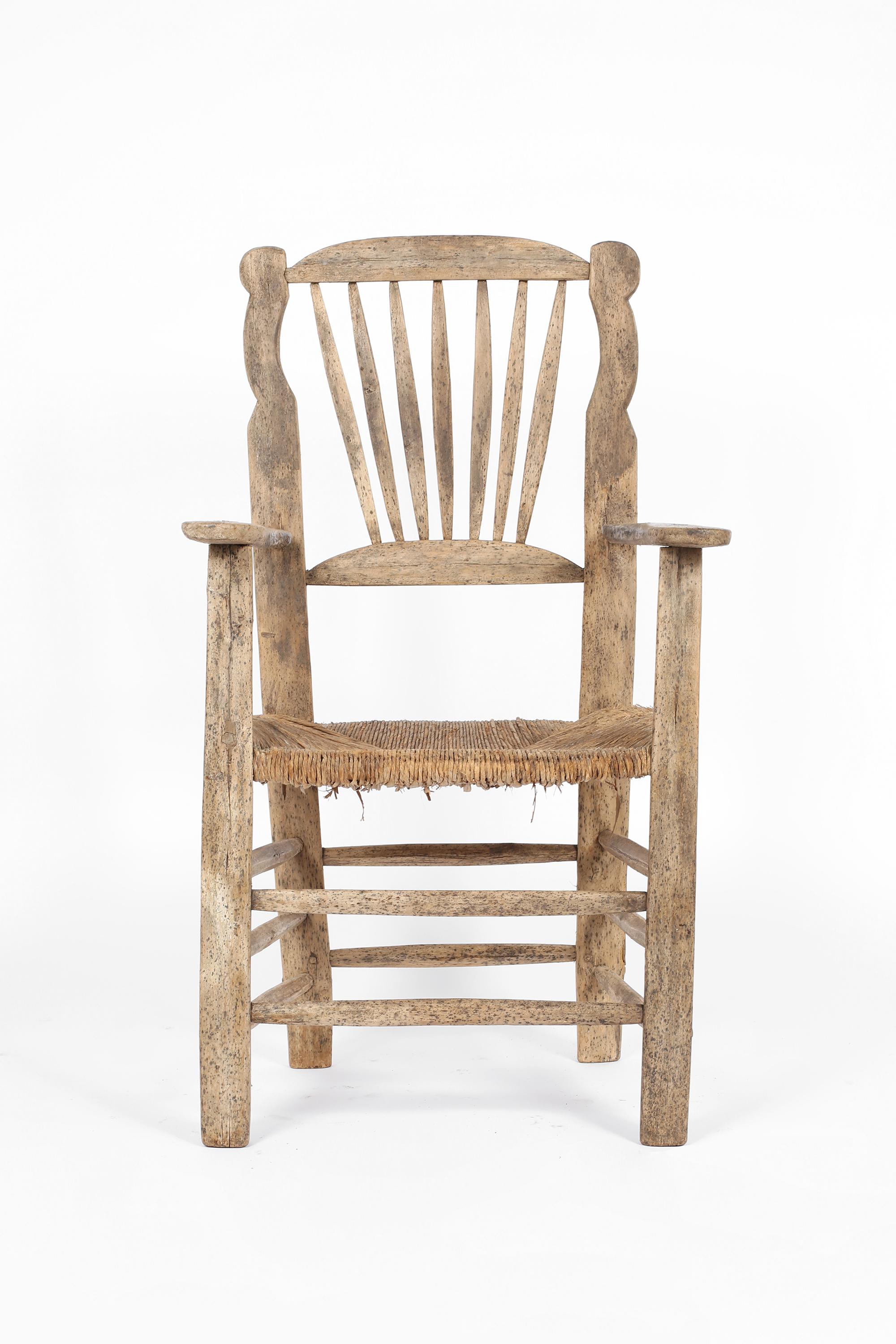 A large, characterful 19th century vernacular chair, primitively constructed from heavily patinated elm with original woven rush seat. Irish, c. 1850.