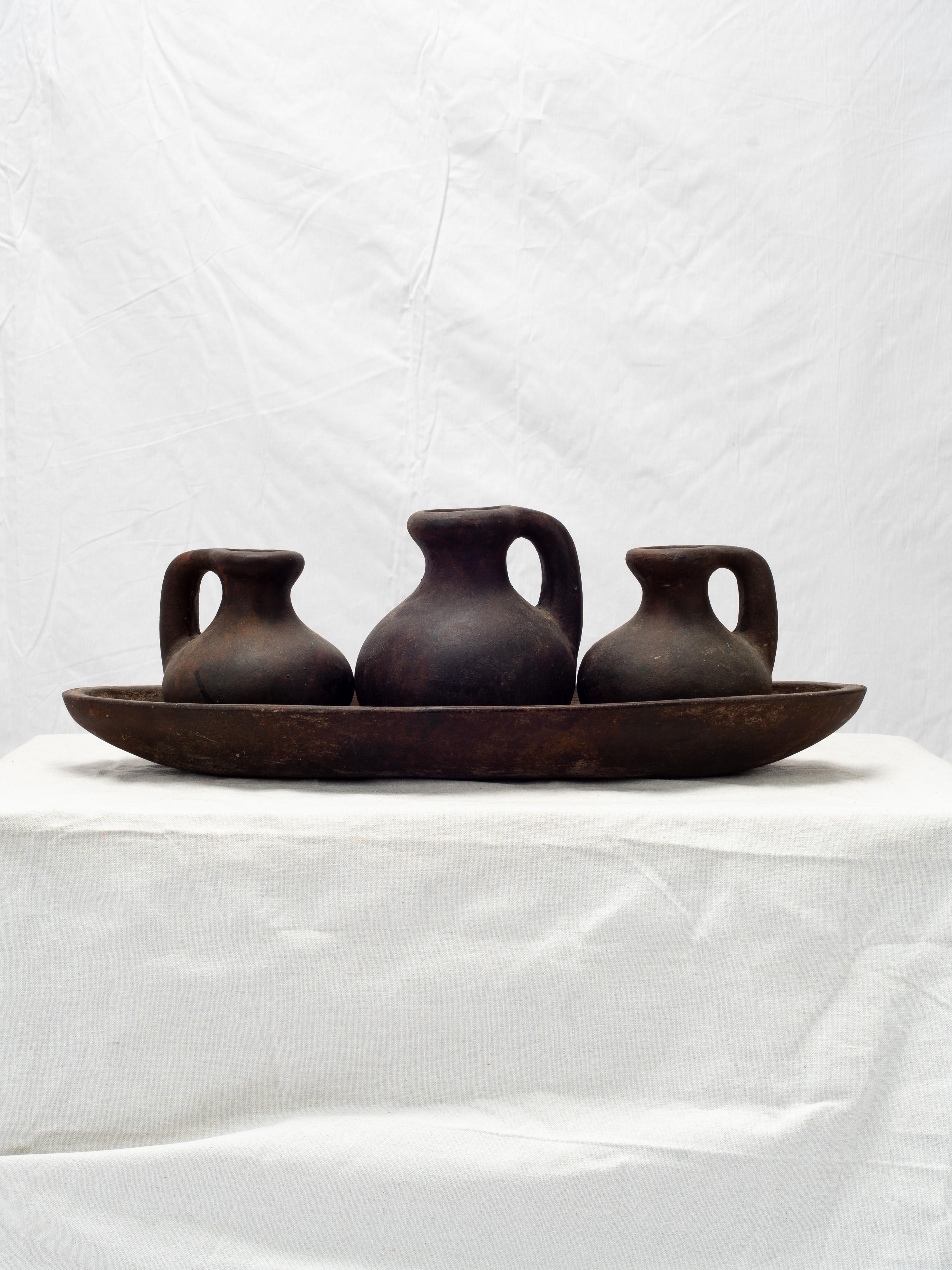 Beautifully primitive set of three black pots in a long dish. The thick clay terracotta pots are made with an oxide finish, providing a textured blackened surface with hints of red tones.

Purchased from a market in Morocco.

