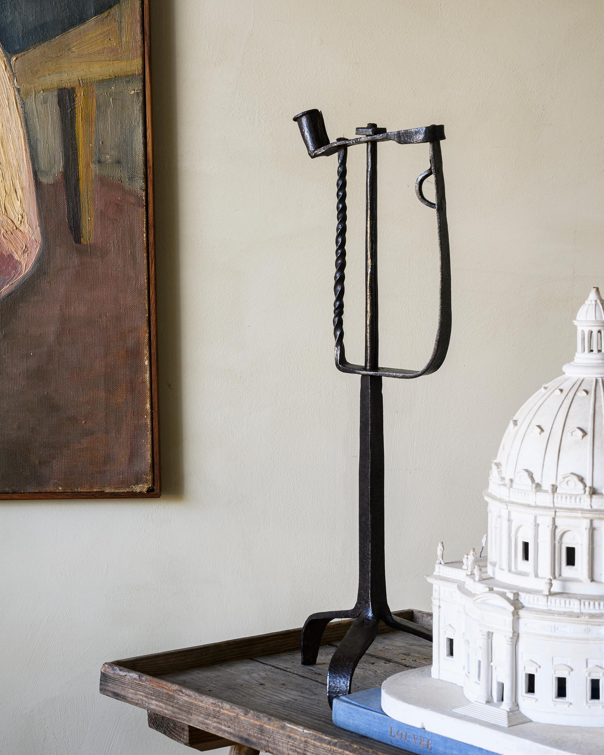 Primitivo y bastante grande candelabro trípode de hierro forjado del siglo XIX, con un casquillo fijo y un soporte de mandíbula con resorte para utilizar el último muñón de la luz de la vela. Hacia 1820 Norte de Europa.